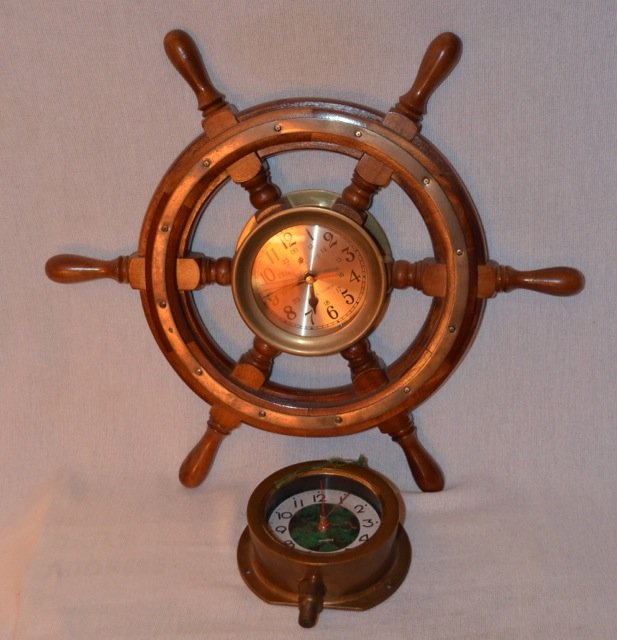 Two Nautical Themed Clocks: A reproduction brass nautical clock; together with a wooden ships wheel with central clock face, marked Ship's Clock. 6-1/2" length; 18" diameter