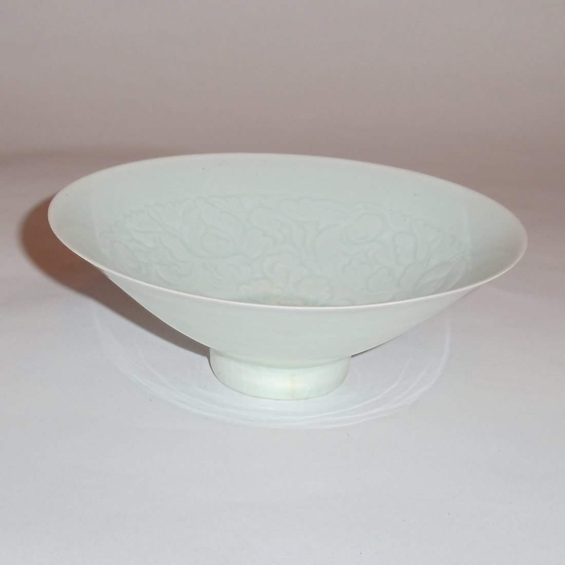 A Qingbai Glazed Bowls with Incised Floral Motifs: A Song Dynasty styled bowl. The Qingbai bowl, shaped like a straw hat, is gracefully glazed in the color of greenish jade. It bears on its inner wall a set of floral motifs. Theses motifs are executed