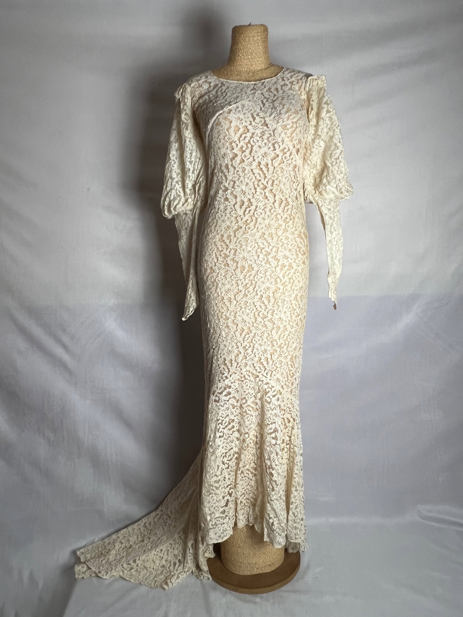 A romantic soft lace dress: The dress appears possibly from the 1970s. The long, fitted silhouette with lace material and long sleeves was popular in that era, especially in bridal and formal wear. The soft, romantic lace and fi