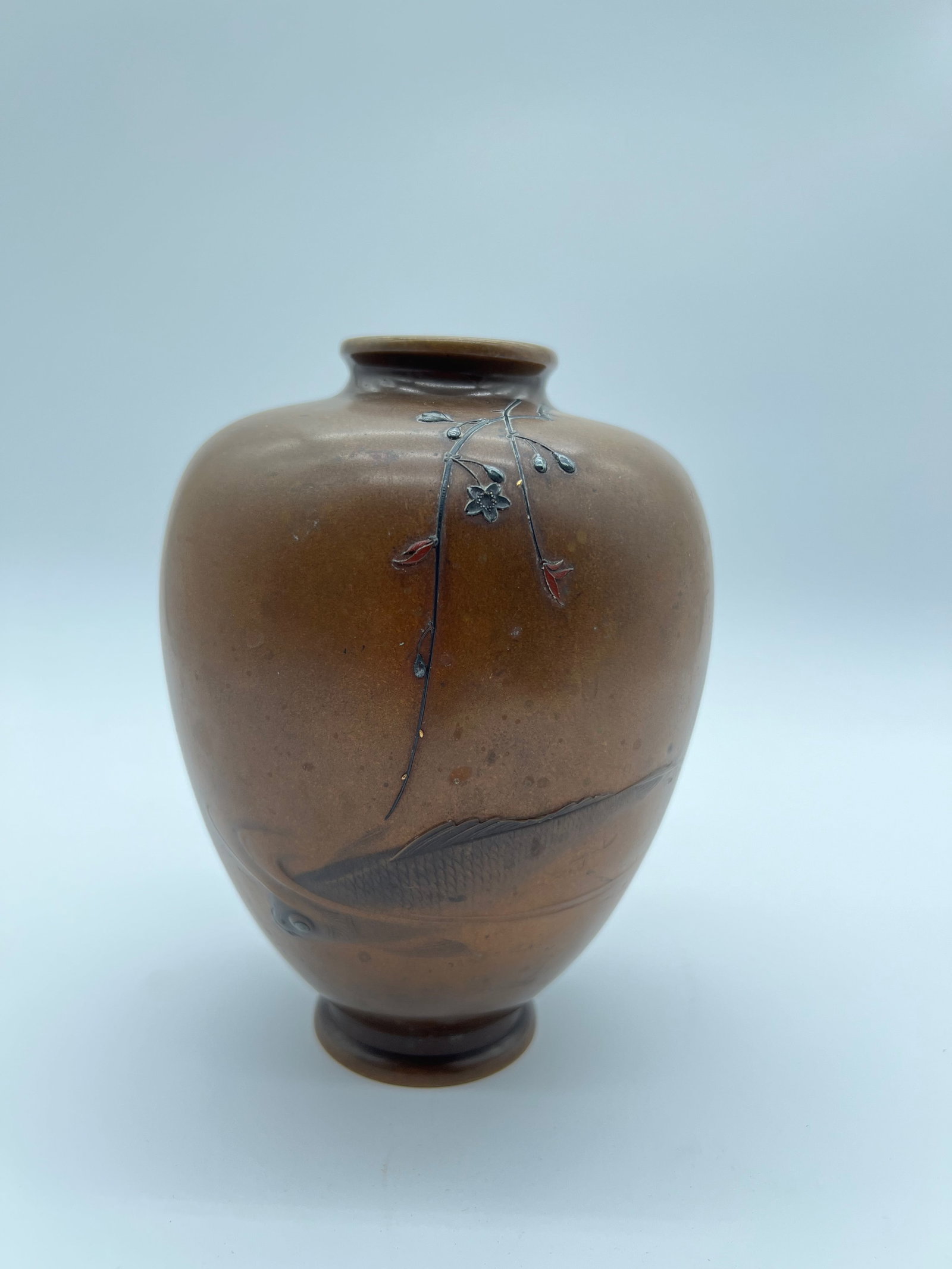 Antique Japanese bronze with silver inlaid vase: The Japanese antique vase with a brownish hue and delicate floral decorations inlaid into its surface. The design appears to feature branches, leaves, and flowers with a mix of subtle colors. Height: 