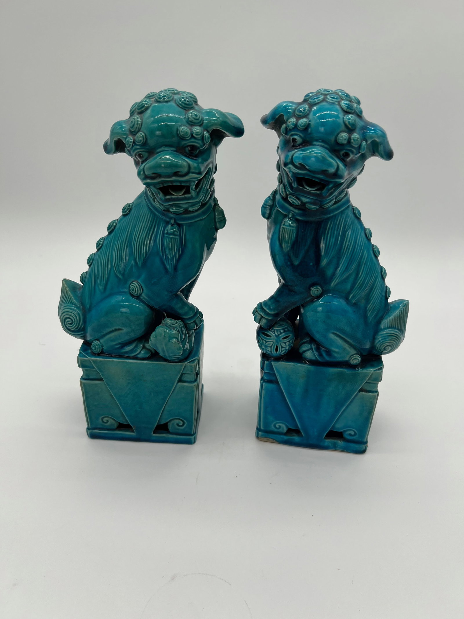A pair of Chinese turquoise porcelain foo dogs: The pair of Foo Dogs are from late 19th, early 20th, symbolic guardians, with the male usually holding a ball (symbolizing the world or power) and the female typically holding a cub (symbolizing nurtu