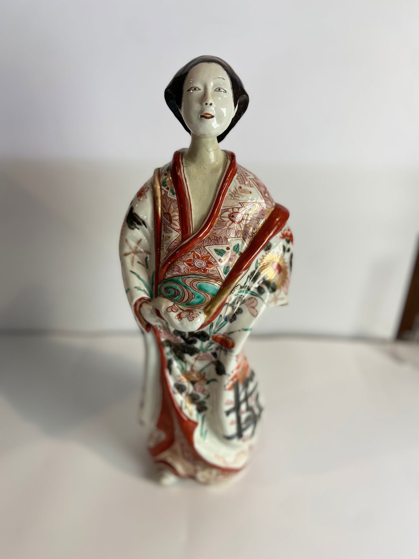 A LARGE JAPANESE IMARI FIGURE OF A BIJIN EDO PERIOD: A LARGE JAPANESE IMARI FIGURE OF A BIJIN EDO PERIOD, 18TH CENTURY The elegant figure smiles gently whilst holding the hem of her robes, her voluminous garments richly decorated in underglaze blue, gil