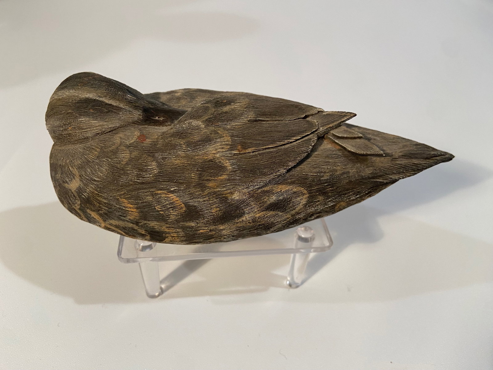 Vintage hand-carved wooden bird in a resting pose decoy: Vintage hand-carved wooden bird in a resting pose, displaying detailed featherwork and naturalistic craftsmanship. The underside features some markings, possibly initials (“TLC”), a date "10-8