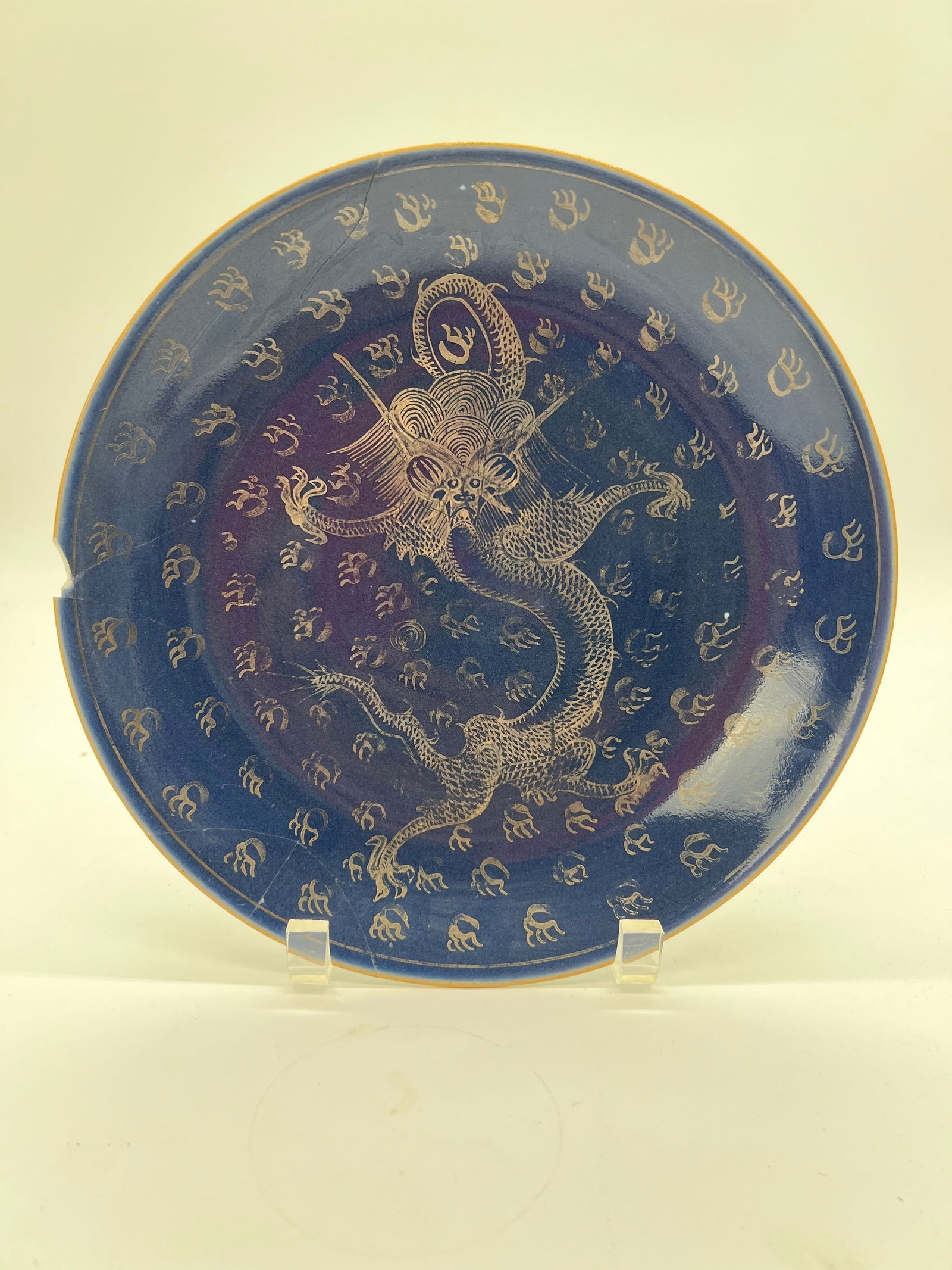 A Chinese blue glazed dragon-themed porcelain plate with JIAQING Six-Character mark: Qing dynasty (1644-1912), The central figure on the plate is a dragon , the dark blue background contrasts with the light-colored possibly gold dragon and surrounding designs. Diameter: 9.5 inches