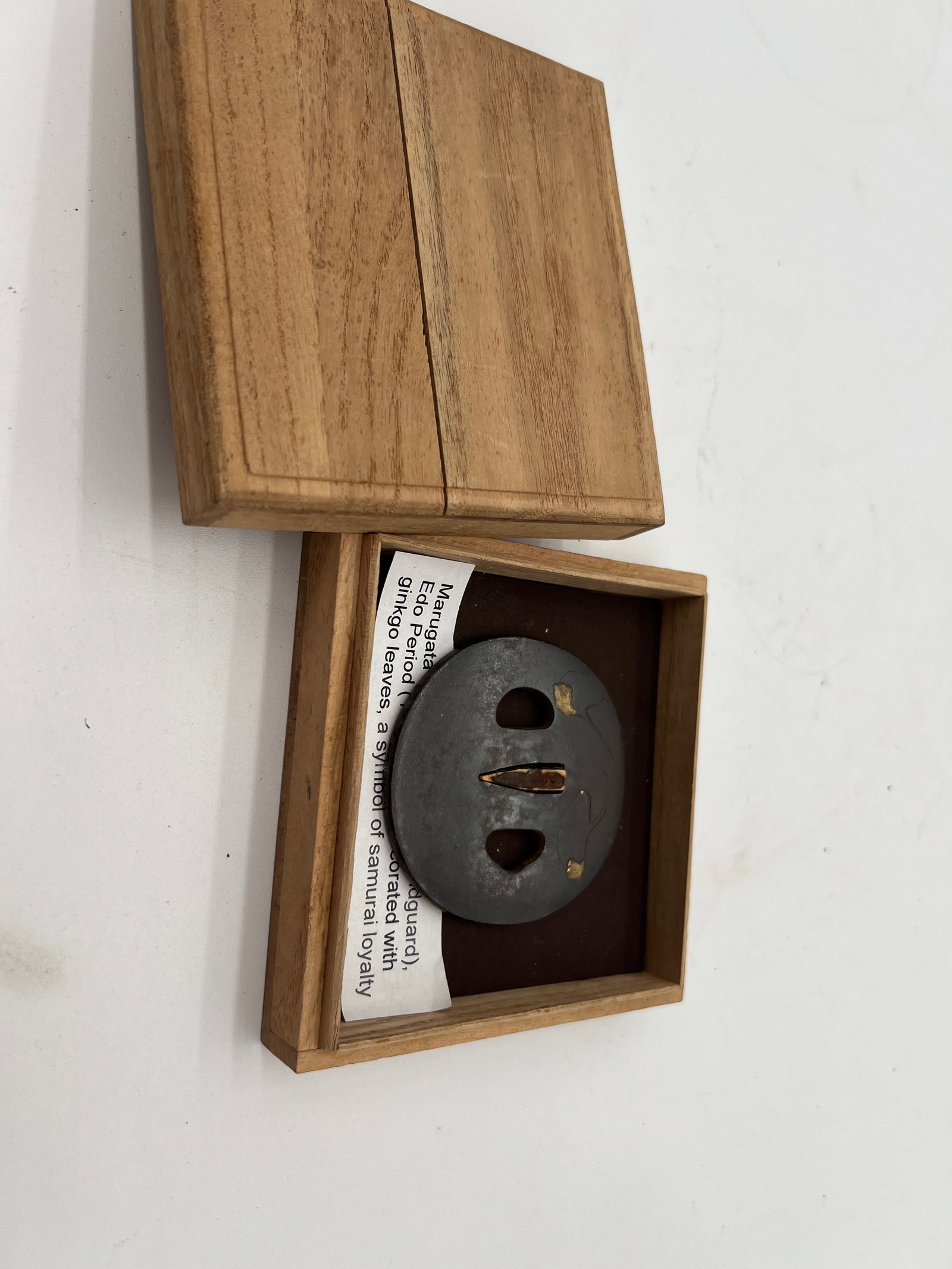 Marugata Iron Gold Inlay Tsuba (sword handguard) Edo Period (1603-1868): This particular tsuba has a minimalist design and signature on it; with some subtle gold inlays or accents that might represent natural motifs or abstract forms. The openings in the tsuba are characte
