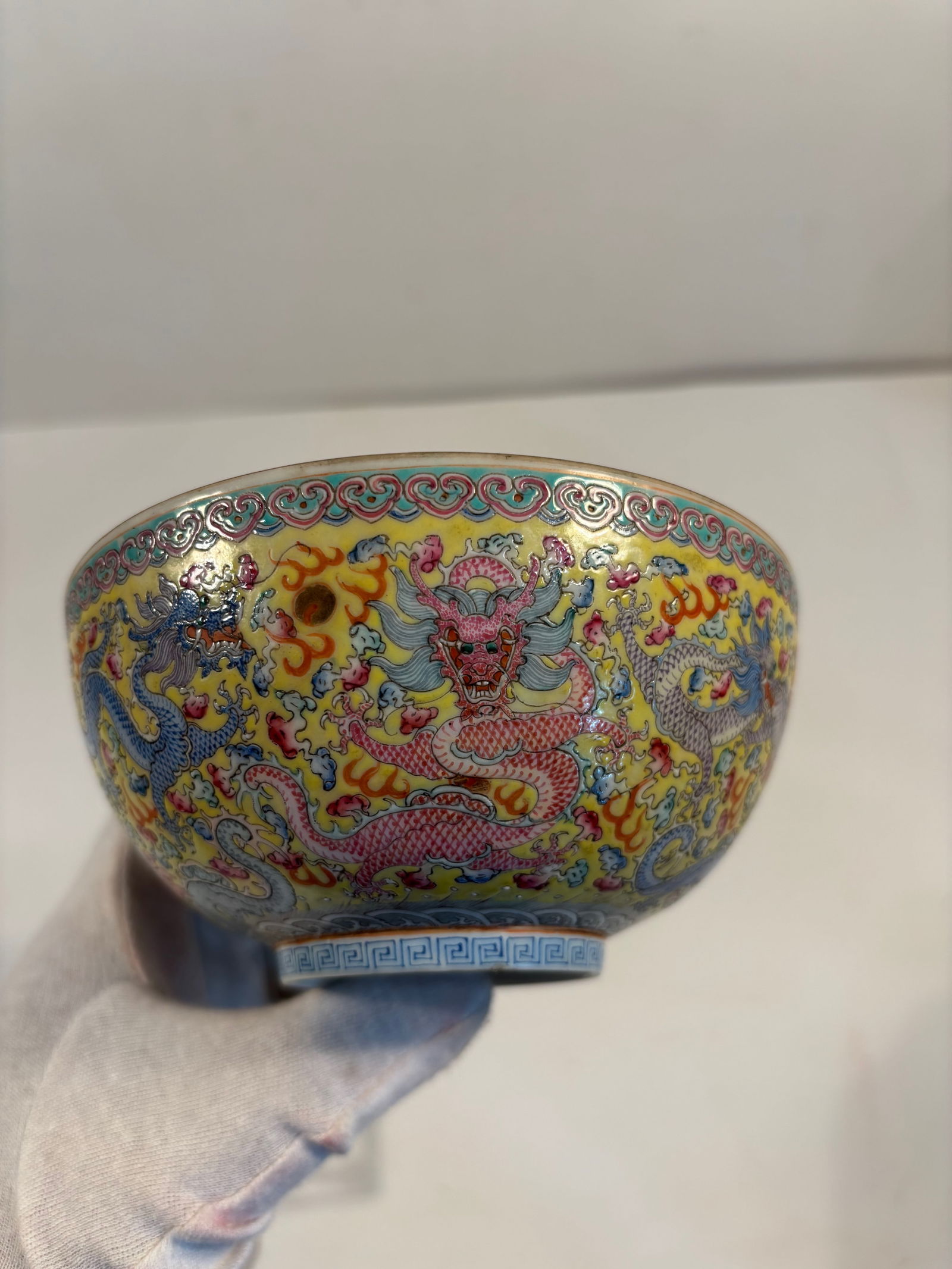 A Chinese porcelain enamel painted dragon bowl with "QIANLONG" mark: Qing Dynasty (1644-1912),The bowl is covered in a vibrant yellow ground with multicolored dragons amid clouds and flames, which is typical of high-quality Qing Dynasty pieces.The interior shows a red