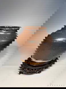 A Chinese Brown Glazed Ceramic Jar: Qing Dynasty(1644-1912); featuring a thick body with a rounded shoulder and short neck. The jar is covered in a rich, dark brown glaze with natural pitting and firing irregularities, characteristic of