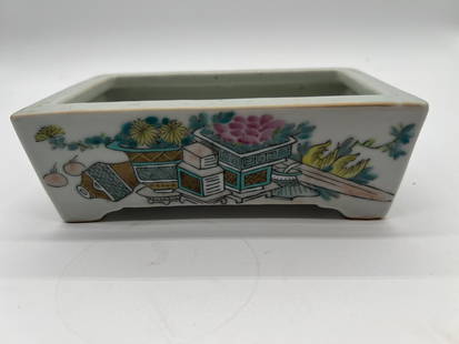 A Chinese QianJiang porcelain rectangular brush washer with artist signed and Iron-red mark: Qing Dynasty (1644-1912); The exterior of the pot features the scholarly objects motif. The objects, including a vase, books, and flowers, are symbolic of education, cultural refinement, and good fort