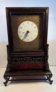 A Large Chinese  MANTLE Clock: Qing Dynasty (1644-1912), set with a white enamel dial set with Roman numerals, with gilt scrolled surround, set within a pierced support, raised upon a wooden stand. 16 INCHES X 12 INCHES X 24 INCHES