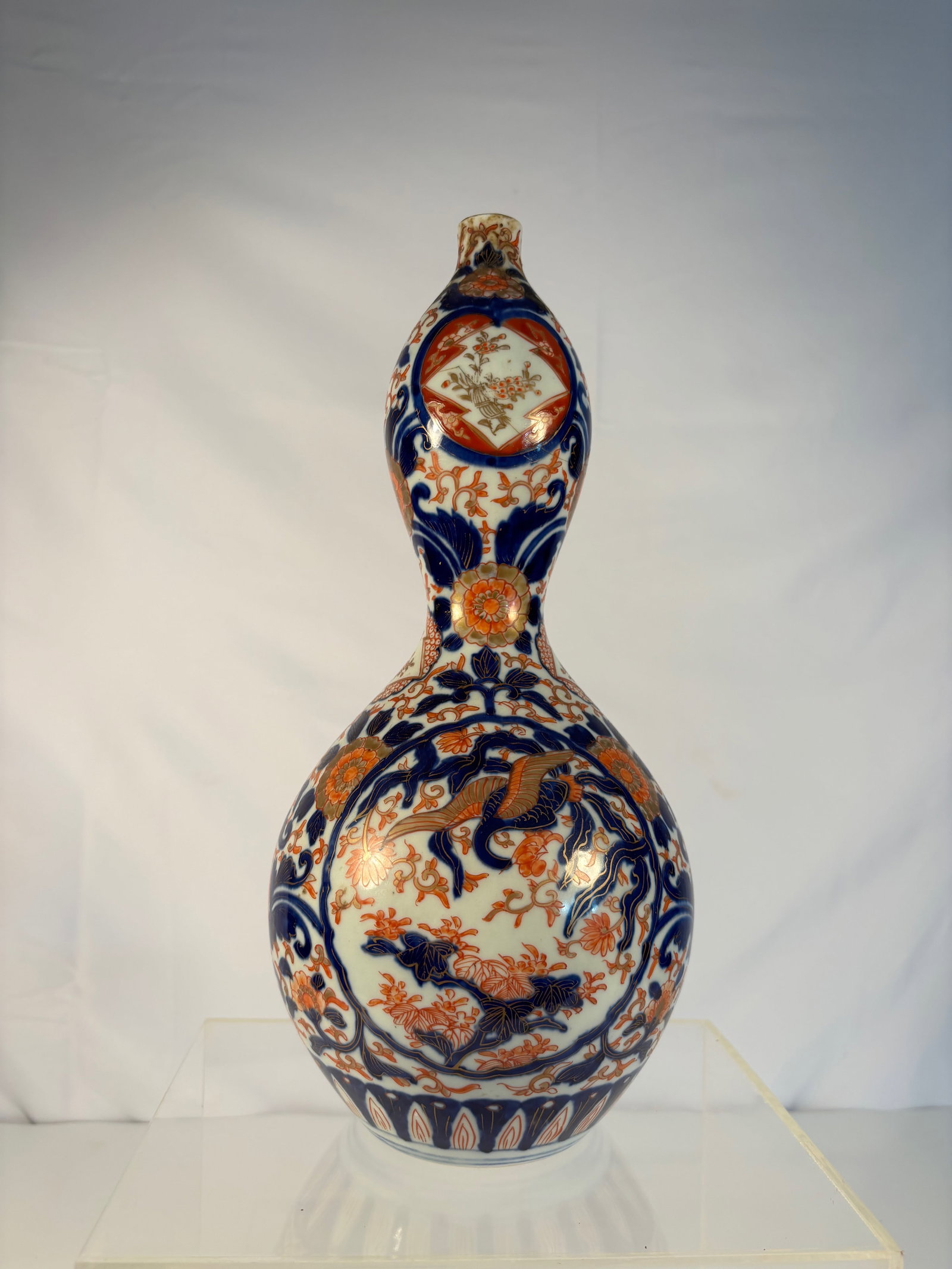 A Japanese Imari Porcelain Double Gourd Vase: Meiji period(1868-1912); Finely painted Japanese Imari porcelain double gourd vase, decorated in iron-red, cobalt blue, and gilt with panels of phoenix amid scrolling peonies, alternating with stylize