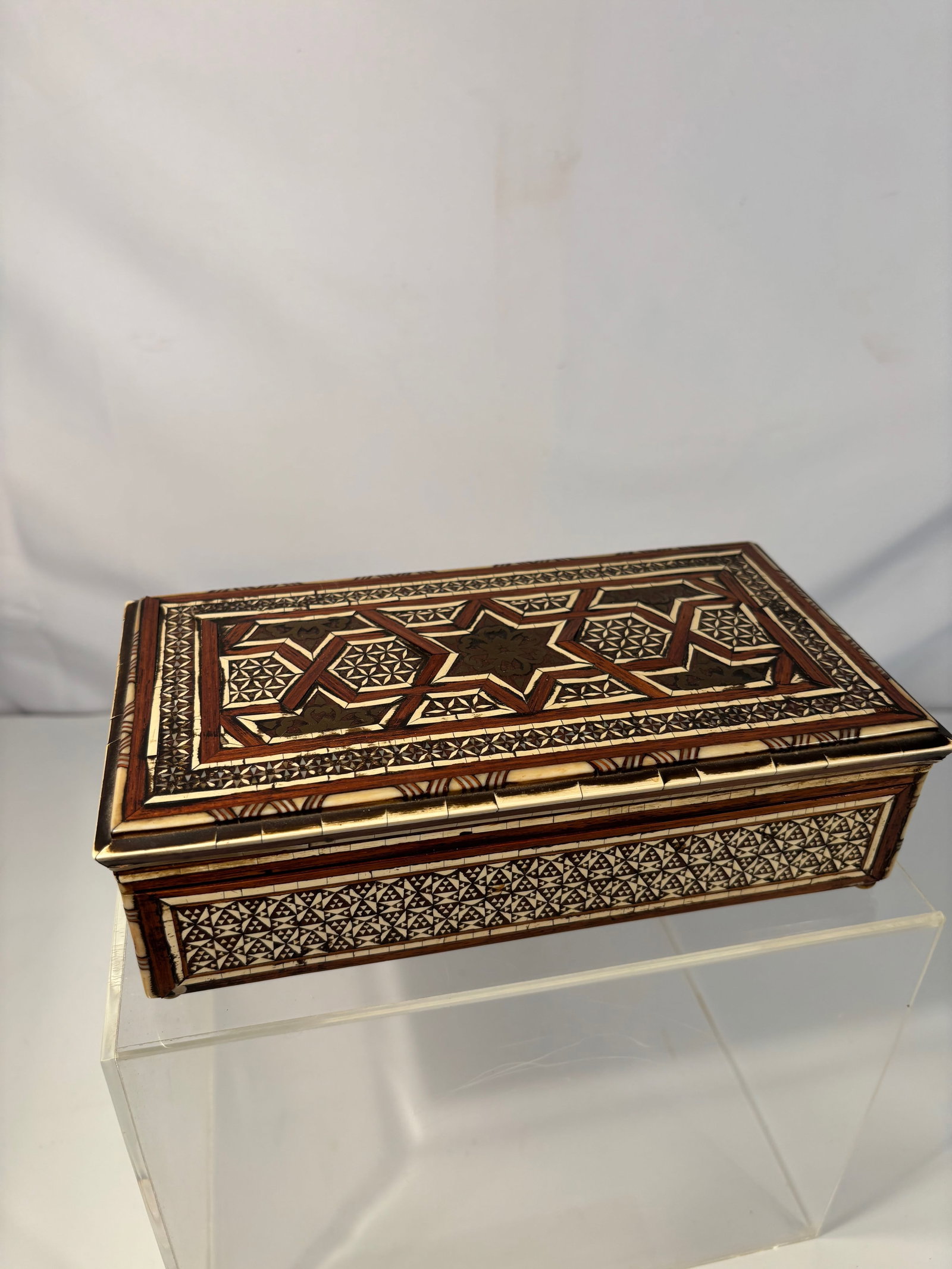 A Middle Eastern Inlaid Wooden Box with Geometric Star Motifs: 19th century to early 20th century;Rectangular Middle Eastern inlaid wood box, decorated with intricate geometric and star motifs in contrasting woods, bone, and possibly mother-of-pearl. The hinged l