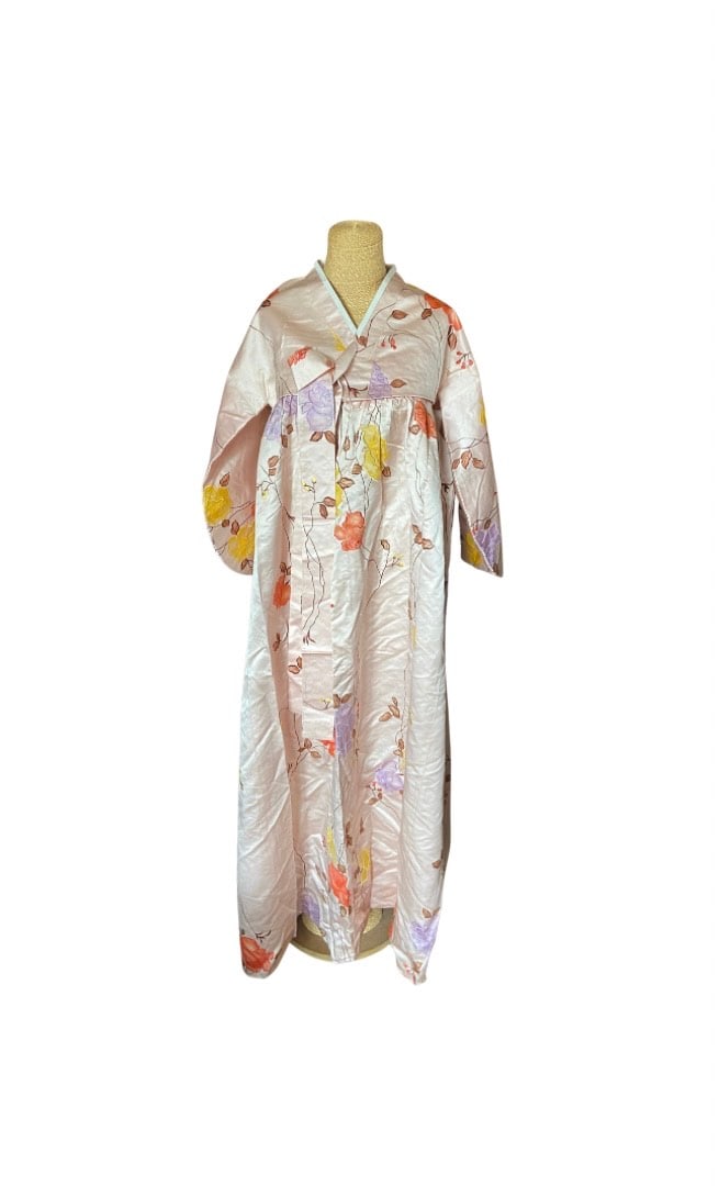 A Vintage Korean Silk Hanbok – Women’s Floral Jeogori & Chima Ensemble: A beautiful vintage Korean hanbok for women, finely crafted from lustrous silk with a delicate floral pattern in shades of red, yellow, purple, and orange on a soft pink ground. This traditional ensem