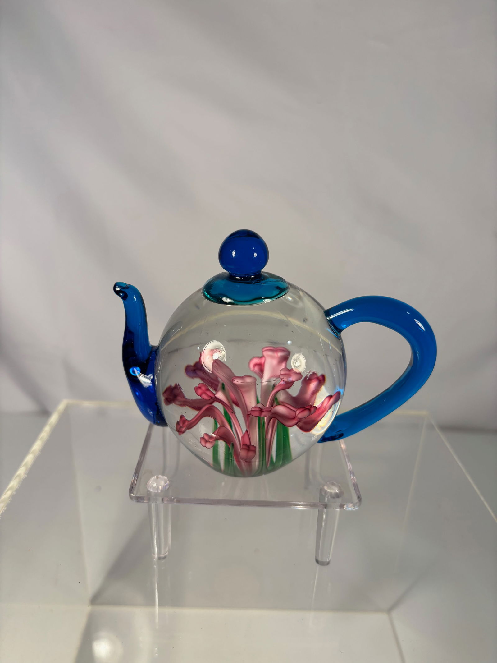 A Dynasty Gallery Glass Teapot Paperweight with Pink Calla Lilies & Blue Handle, Heirloom: Delightful Dynasty Gallery collectible glass paperweight crafted in the form of a miniature teapot. Inside the clear glass body are vibrant lampwork pink calla lilies with green stems, beautifully det
