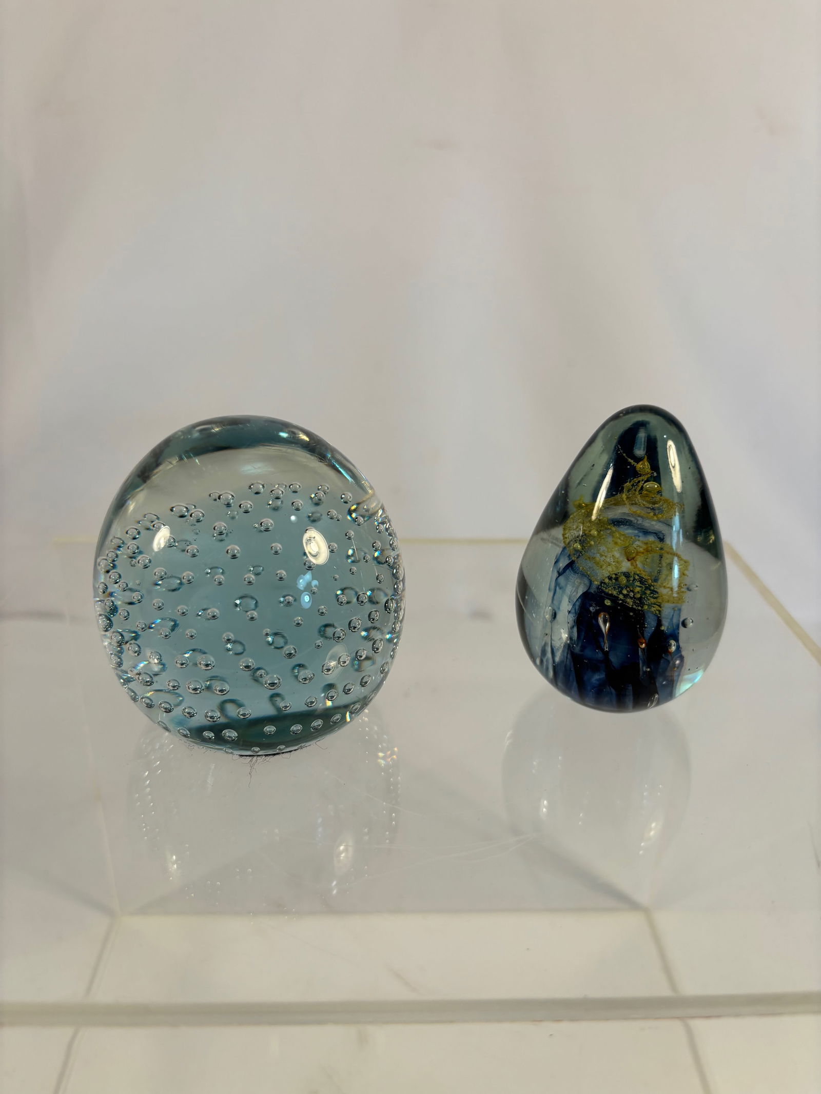 Lot of 2 Art Glass Paperweights — Controlled Bubble Sphere and Blue-Gold Teardrop Form: Lot of 2 contemporary art glass paperweights, one in a clear spherical form with uniform controlled bubbles, and the other in a teardrop shape with deep cobalt-blue core accented by suspended gold and