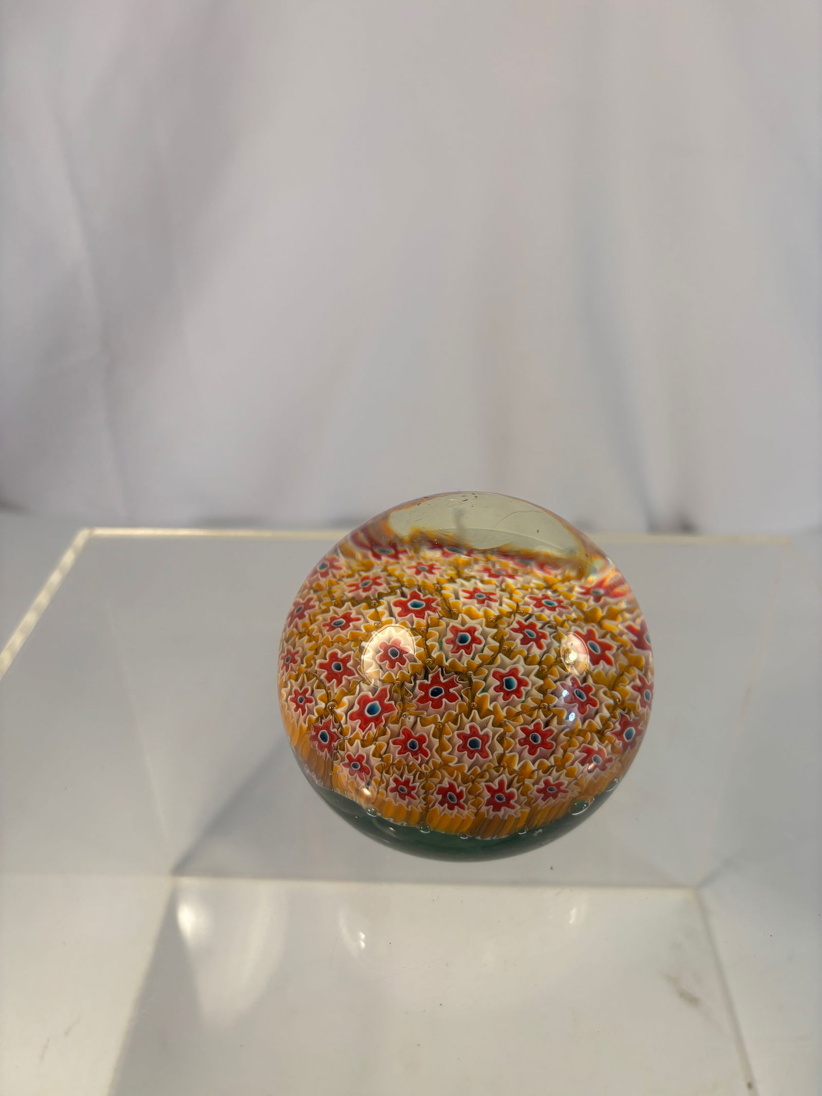 Murano Millefiori Cogwheel Art Glass Paperweight, Mid-20th Century: A finely crafted Italian Murano millefiori paperweight of domed circular form, featuring tightly packed concentric rows of red, white, and yellow cogwheel canes forming a floral pattern under clear gl