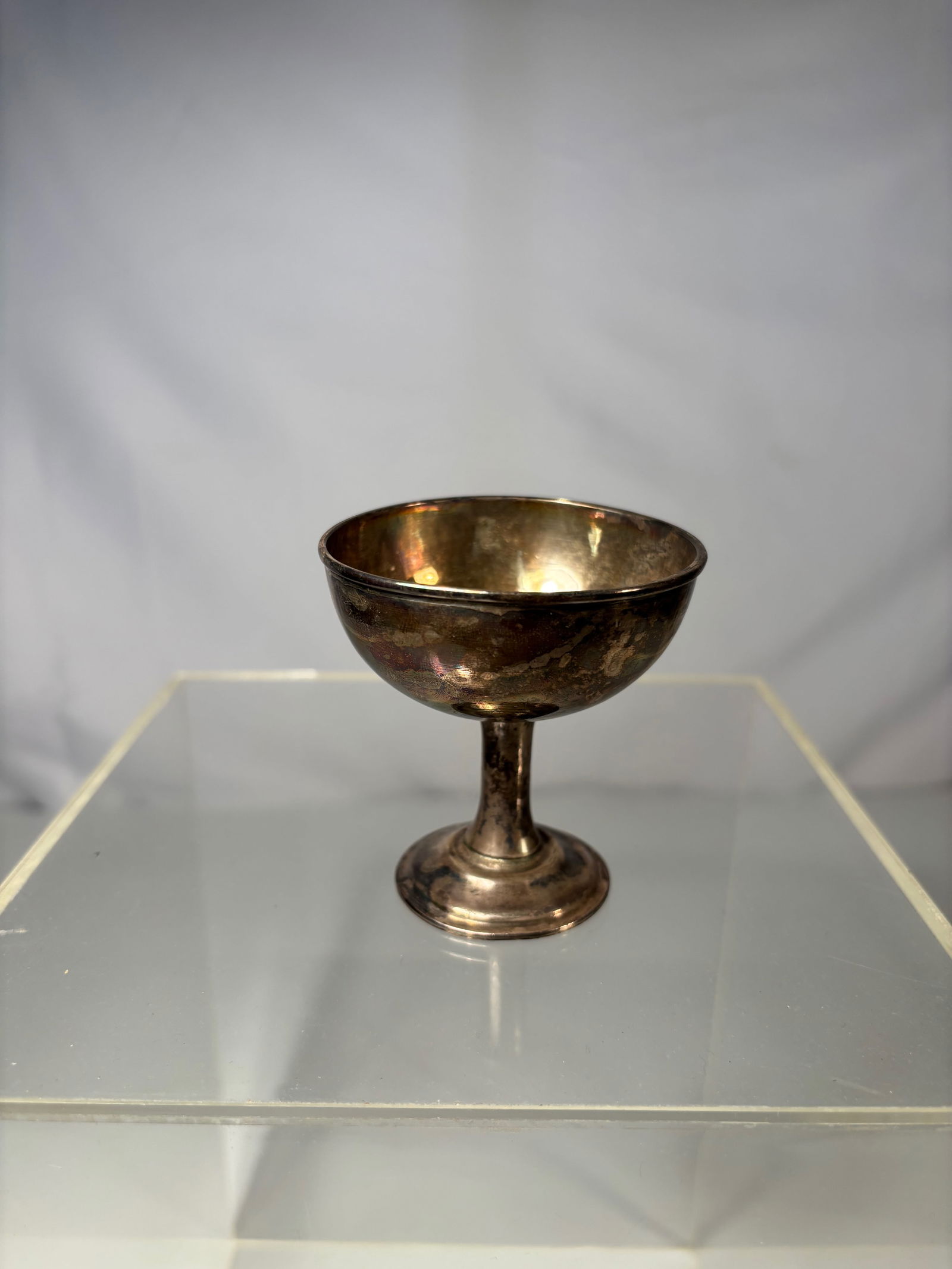A Chinese Sterling Silver Goblet, Marked" shang zu yin": Early 20th Century, A petite, stemmed goblet featuring a rounded bowl and flared foot, finished with a warm, aged patina. The underside bears stamped hallmarks"SHANG ZU YIN" . ?Dimensions?Height: 2.65