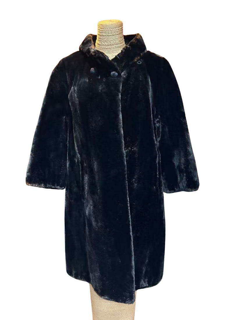 Black Sheared Mink Fur Coat with Shawl Collar size M: A classic black sheared mink fur coat featuring a soft, velvety finish and an elegant shawl-style collar. The coat has a straight, mid-length silhouette with gently flared sleeves, creating a timeless