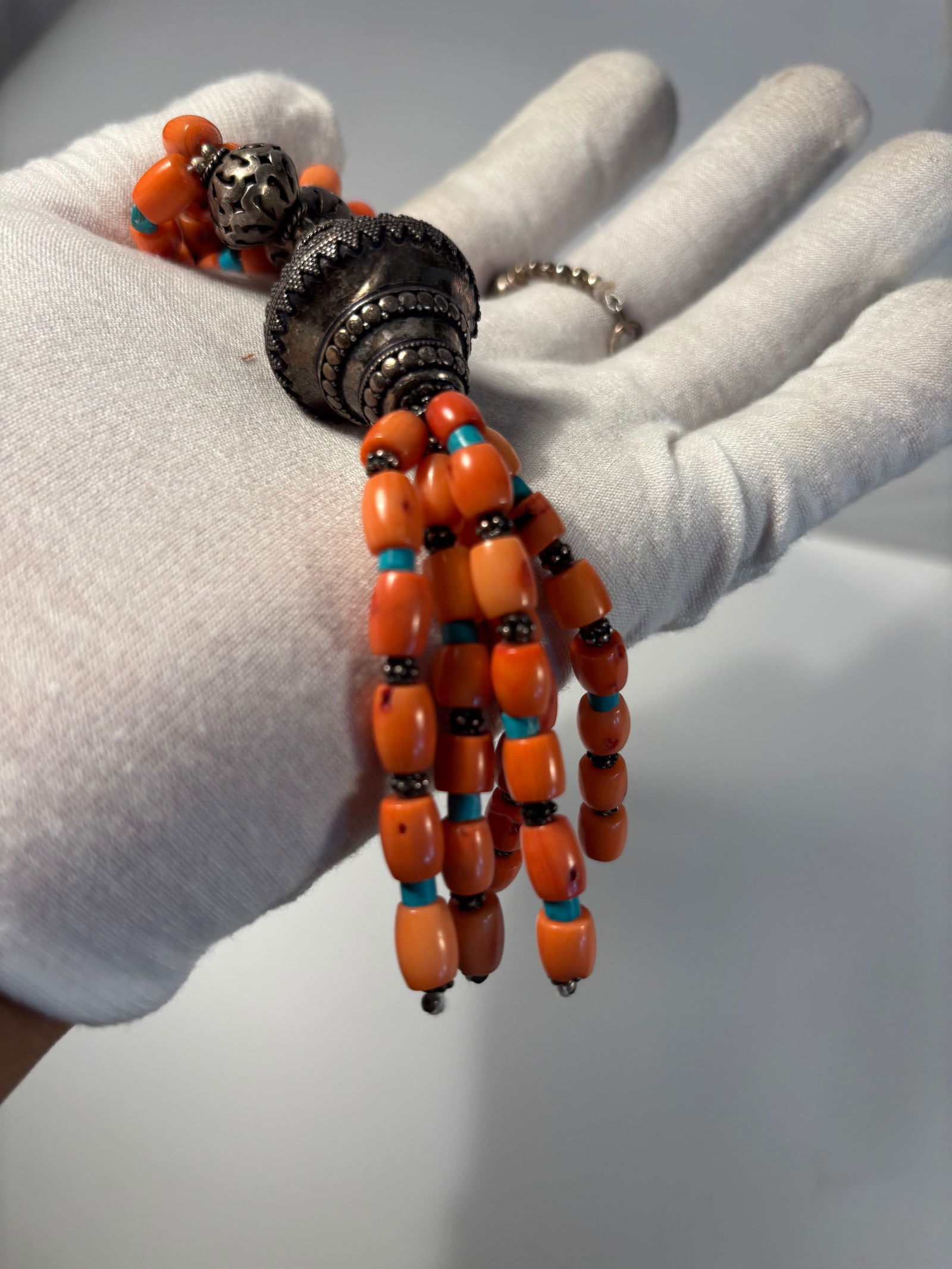 Four-Strand Coral and Turquoise Bead Necklace with Silver Filigree Elements: Striking four-strand necklace composed of polished orange coral beads, accented with small turquoise spacers and ornate silver filigree beads. The necklace is centered with an elaborate silver filigre