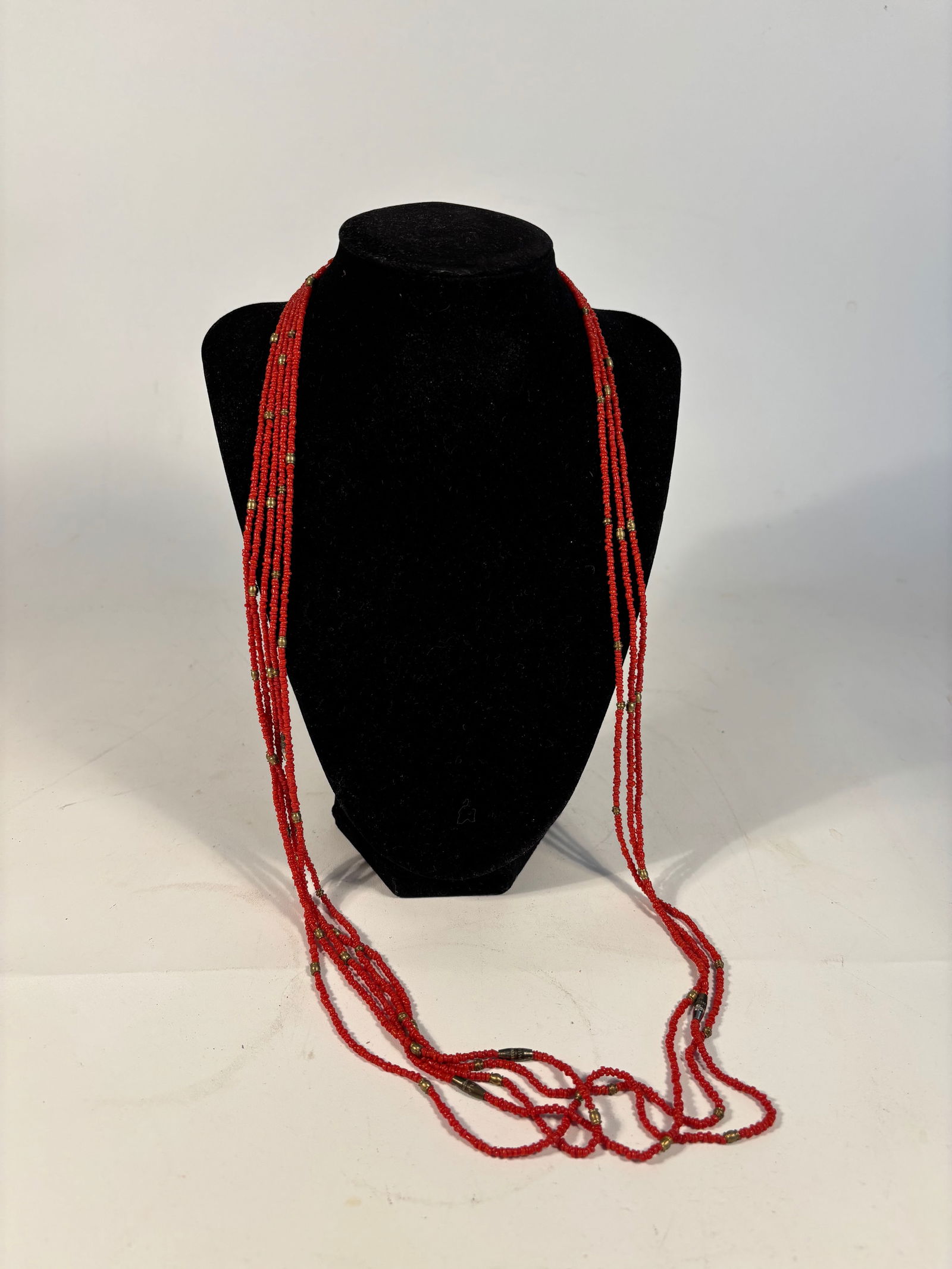 multi-strand red coral necklace: Elegant multi-strand necklace composed of natural, undyed red coral beads, accented with gold-tone metal spacer beads. The rich, organic red hues and fine craftsmanship reflect a timeless ethnic-inspi
