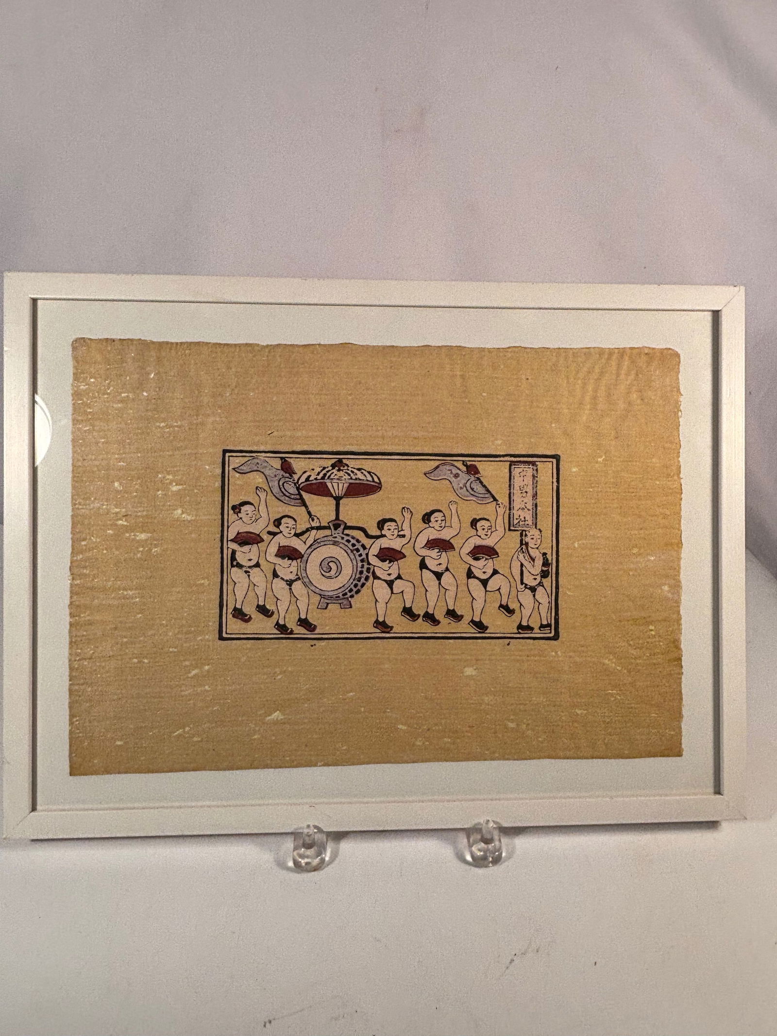 Japanese Folk Woodblock Print of Festival Dancers, Framed: A Japanese folk woodblock print depicting a lively procession of festival dancers surrounding a large taiko drum cart, with decorative banners and stylized figures. Rendered in the charming, simplifie