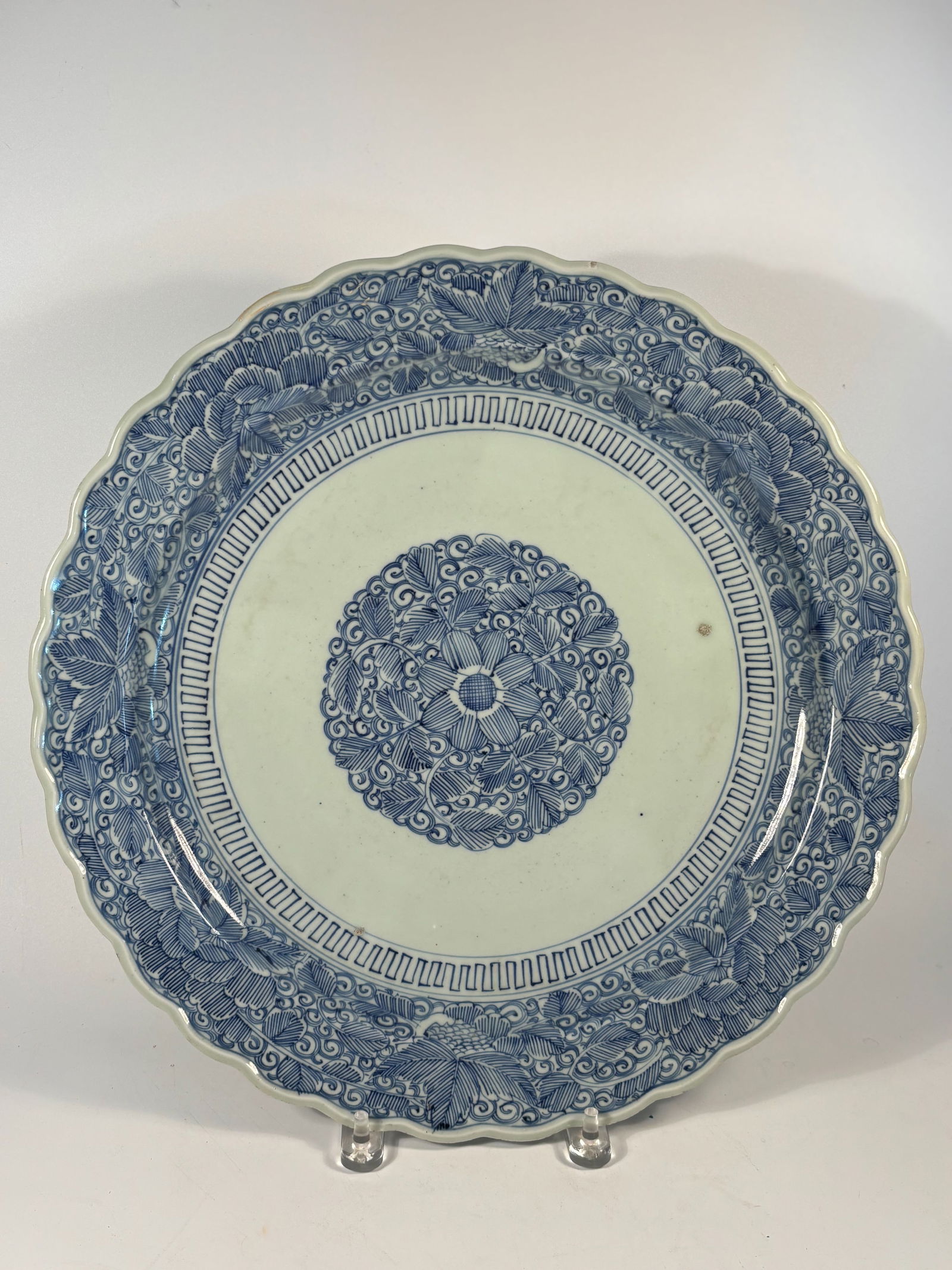 A large Japanese Arita Blue and White Porcelain Plate with mark: 19th Century, A finely painted Japanese Arita porcelain plate featuring a central floral medallion surrounded by elaborate scrolling lotus and foliage designs in deep underglaze blue. The rim is folia