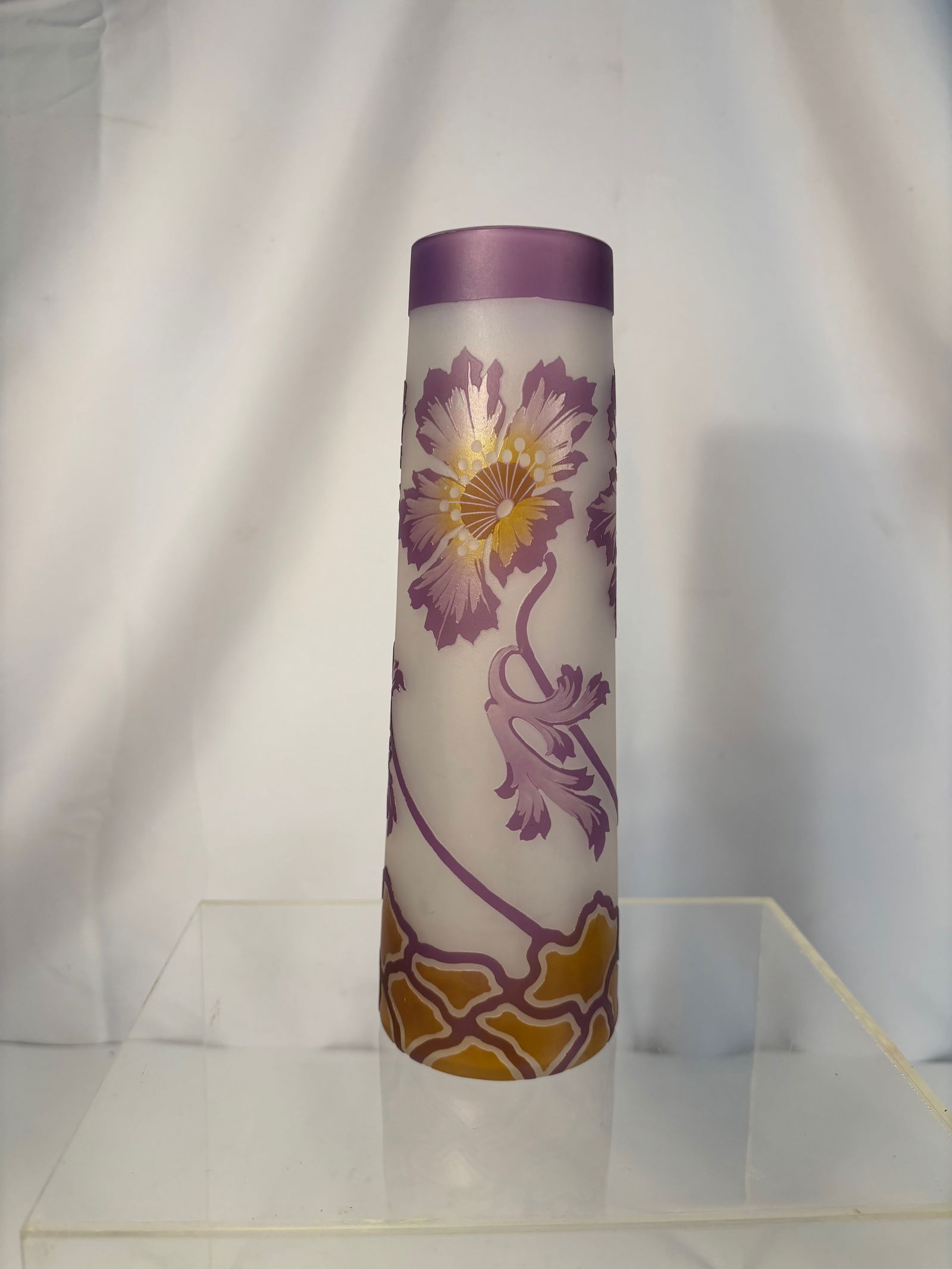 A Daum Nancy 9-Inch Art Nouveau Cameo Glass Vase, Violet & Amber Floral, c. 1905–1910: Cylindrical cameo glass vase in frosted ground overlaid in amethyst and amber, acid-etched and polished to a high relief with large chrysanthemum/pansy-type blossoms, scrolling stems and leaves; shade