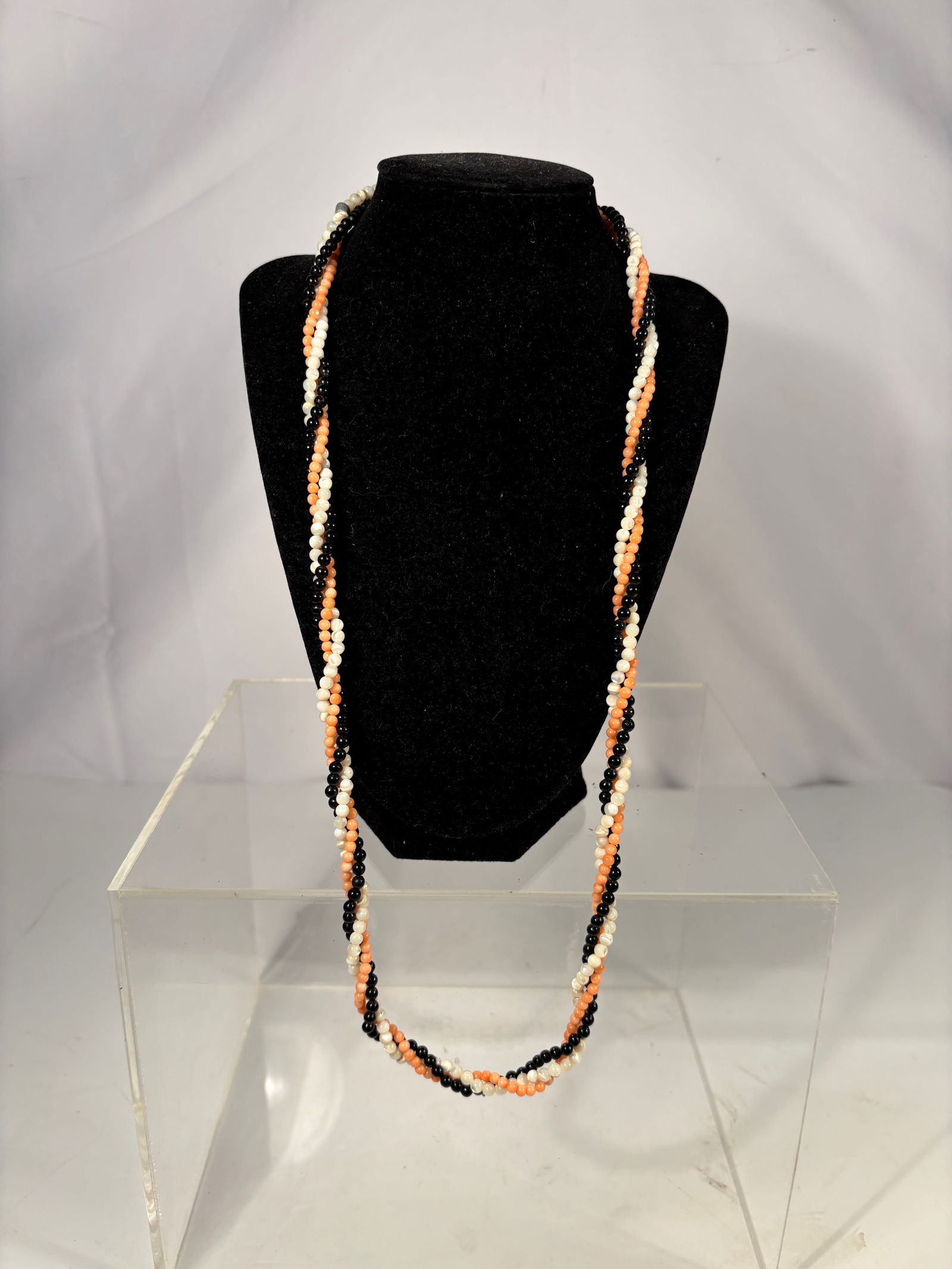 Twisted Multi-Strand Coral, Pearl, and Onyx Necklace: Twisted multi-strand necklace composed of peach coral beads, white freshwater pearls, and black onyx beads. The strands are braided together to create a contrasting color pattern, finished with a gold