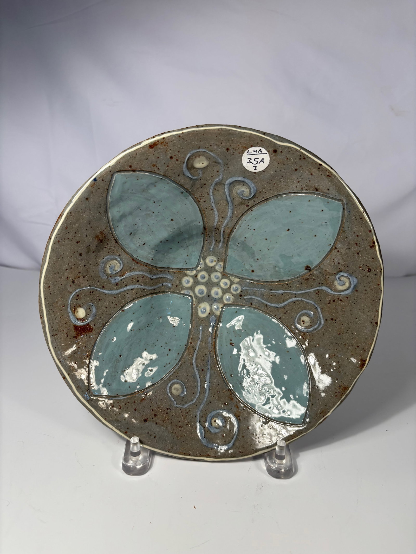 A pottery bowl with Turquoise Floral Design: Early 20th century, Of shallow circular form, the interior decorated with a stylized four-petal floral motif in turquoise and white slip, outlined with incised lines and swirling tendrils against a sp