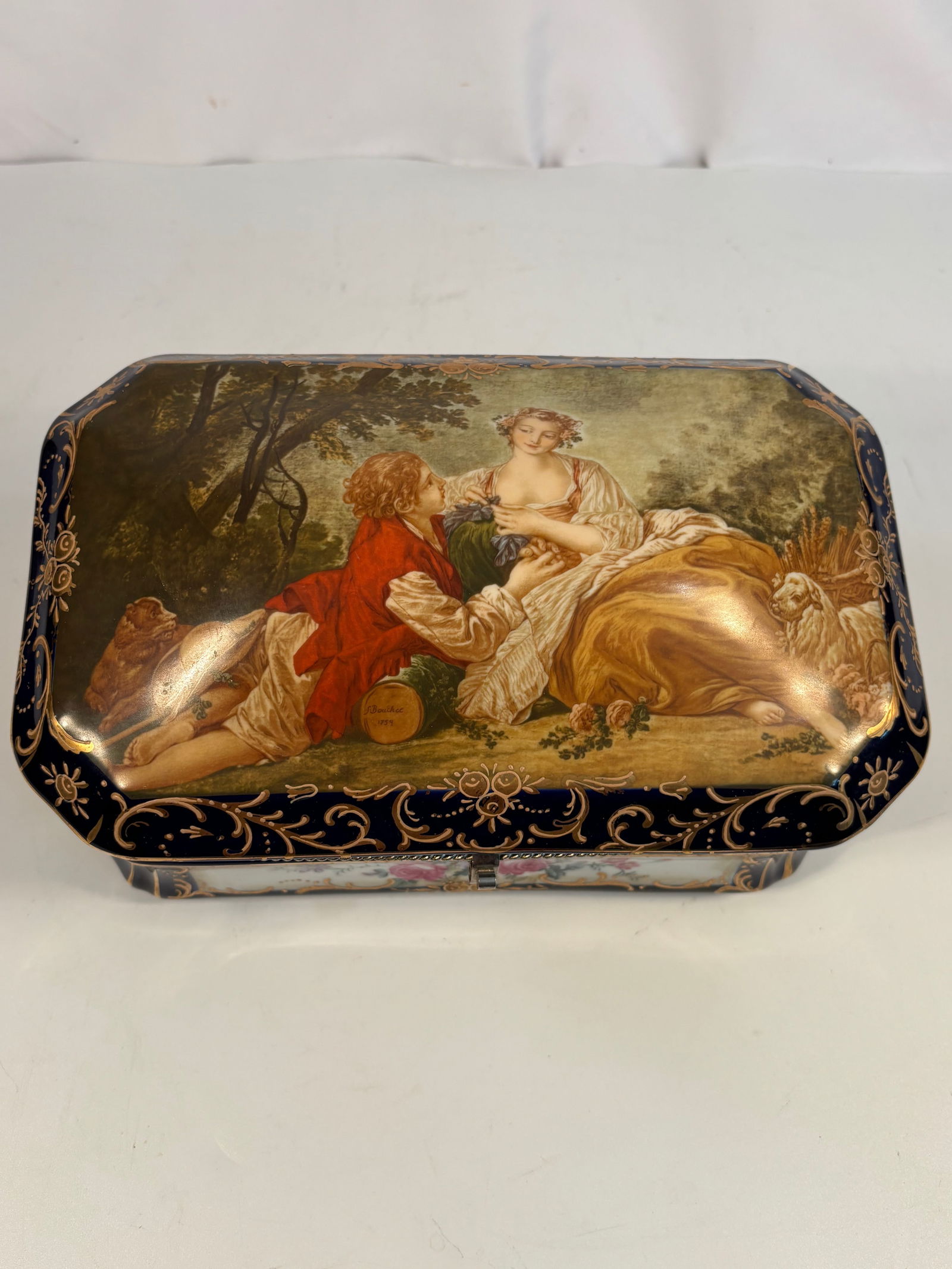 A RS Prussia Cobalt and Gilt Porcelain Jewelry Box with Courting Scene, ca. 1900: of rectangular form with canted corners, featuring a romantic courting couple in a garden on the lid, framed by rich cobalt-blue ground and intricate raised gilt scrollwork and floral