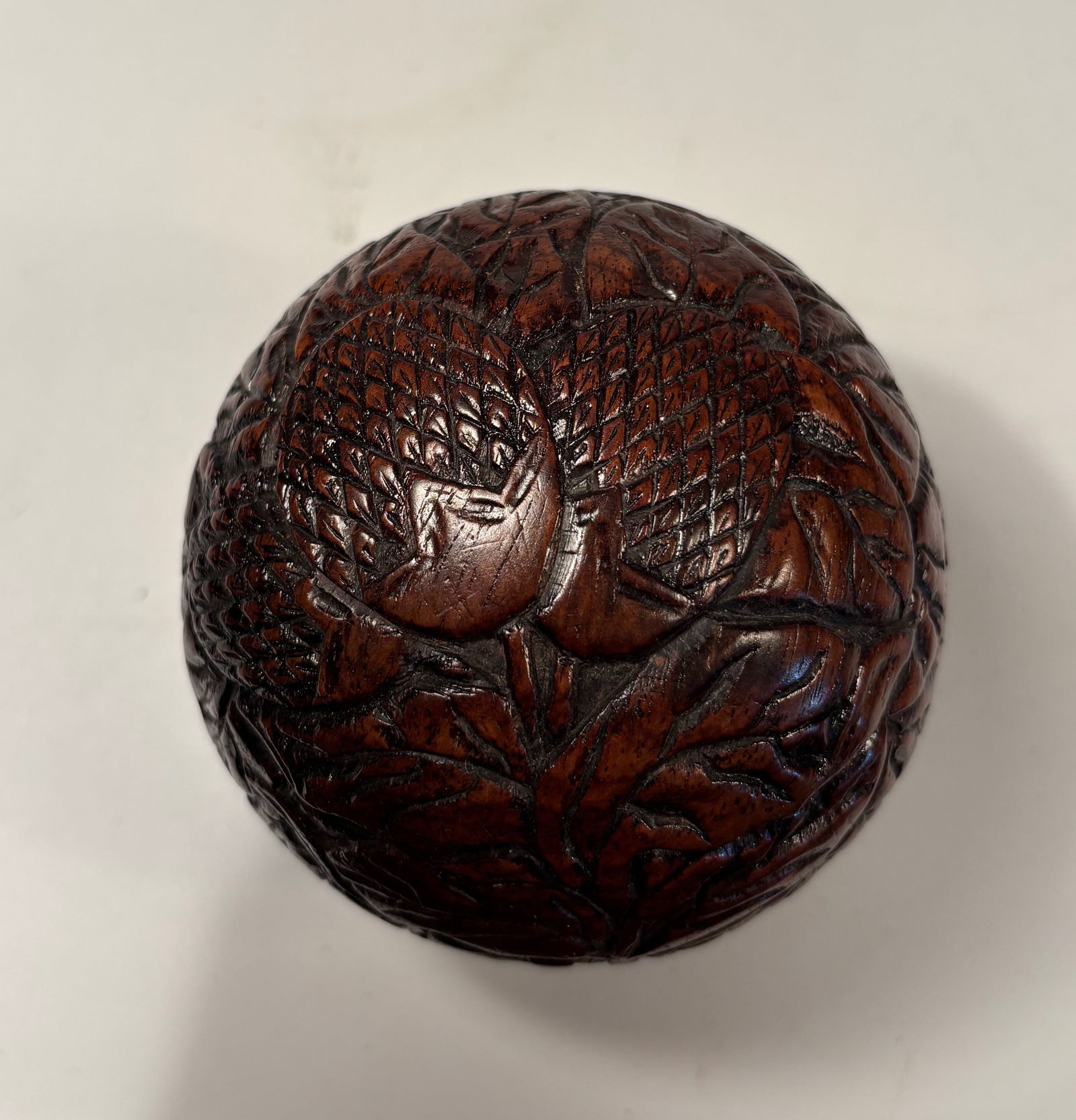 A Chinese hand carved huanghuali box: QING DYNASTY(1644-1912); A finely carved Chinese box made from huanghuali wood, shaped in the form of a naturalistic fruit or seed pod, with high-relief carving of overlapping leaves and scaled surfac