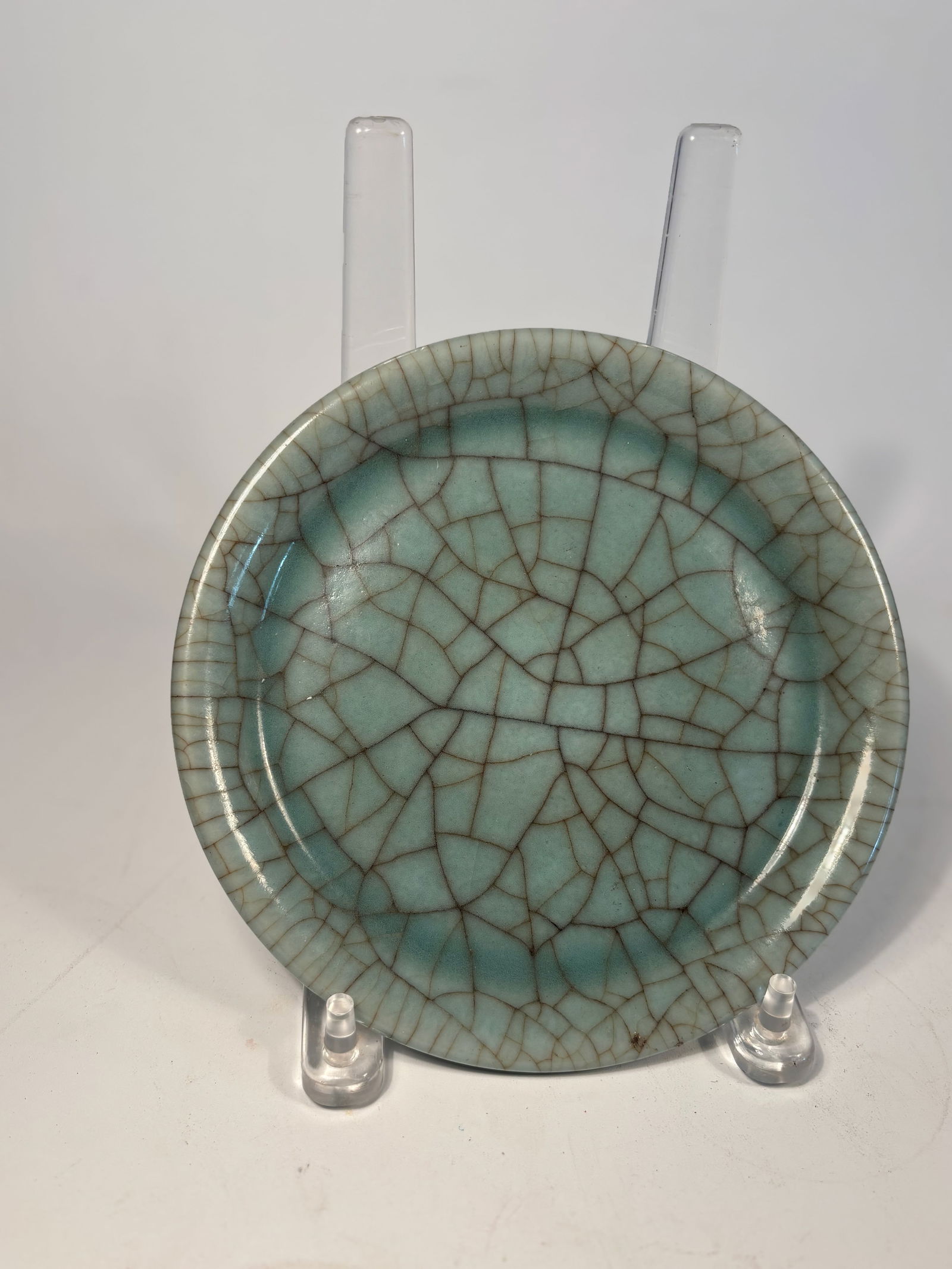 A Chinese Celadon Dish with Crackled Glaze Plate: Ming dynasty(1368-1644) to Qing dynasty (1644-1912); A Chinese celadon-glazed dish,of shallow circular form with a broad, slightly everted rim. The body is covered overall in a thick, pale grayish-gre