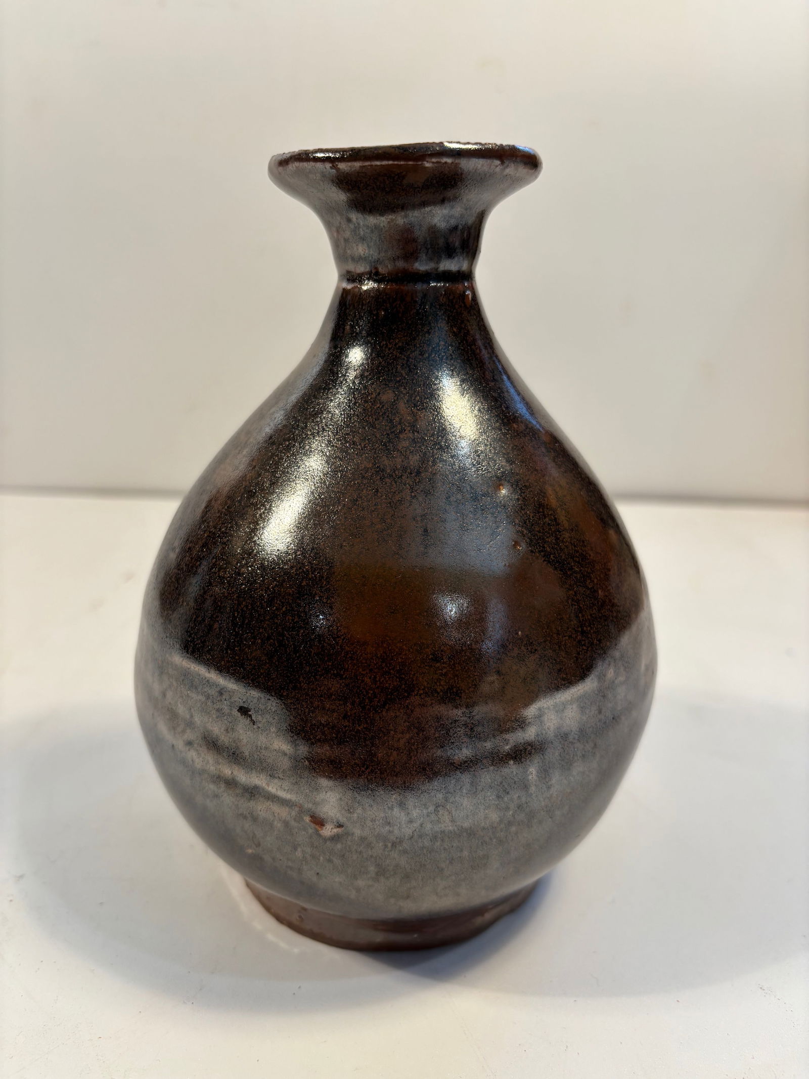 A Chinese Ceramic brown glazed wine vase: Qing Dynasty (1644-1912) or early ; Globular body with a narrow neck and flared mouth;The footrim is unglazed and shows signs of kiln grit and age. The glazed base with natural pitting and uneven