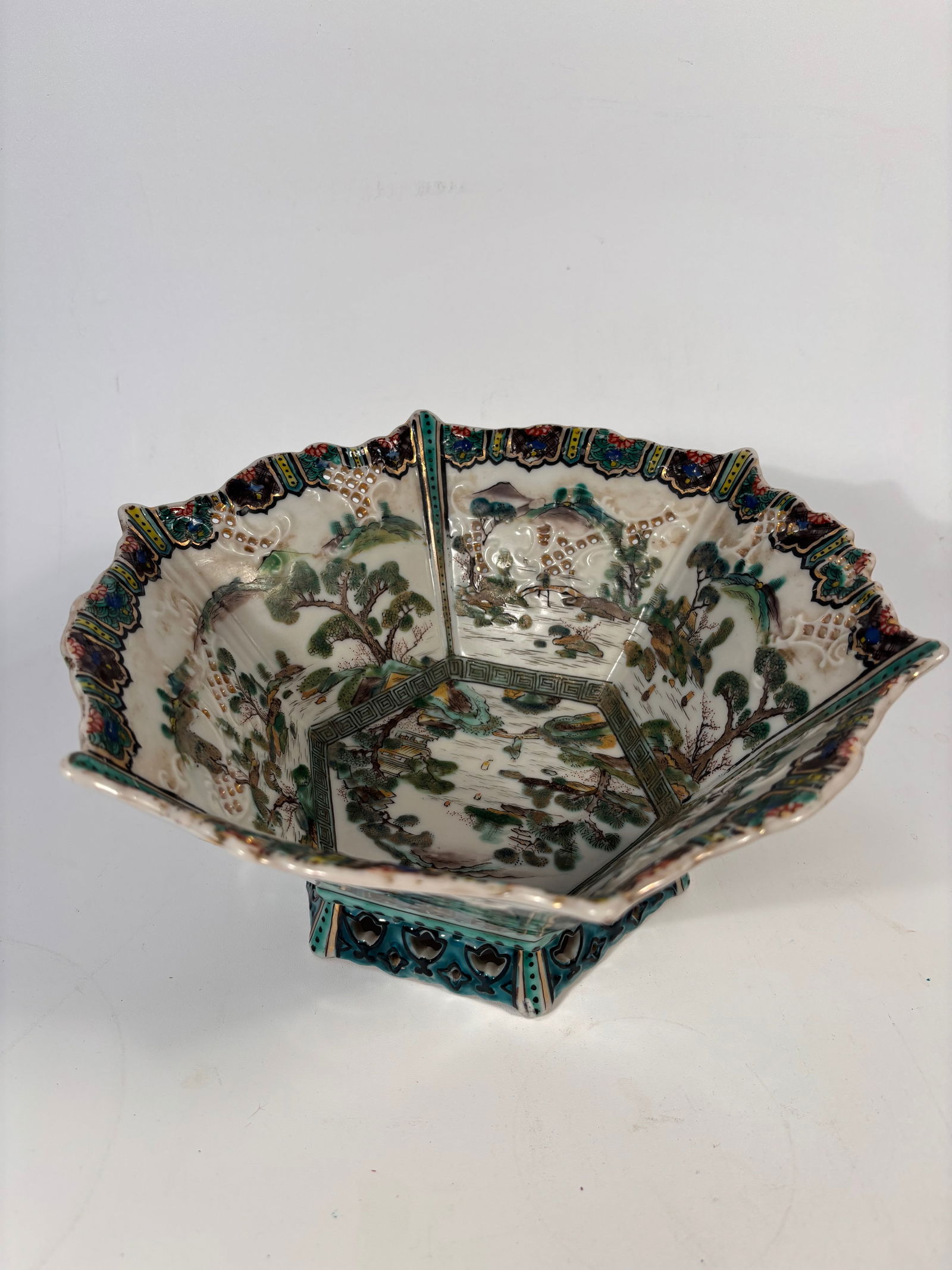 A Chinese Famille Verte Reticulated Hexagonal Porcelain bowl: Qing Dynasty (1644-1912);The hexagonal form with reticulated (pierced) rim , The inner landscape scene—featuring mountains, scholars, pavilions, and pine trees—is executed in famille verte