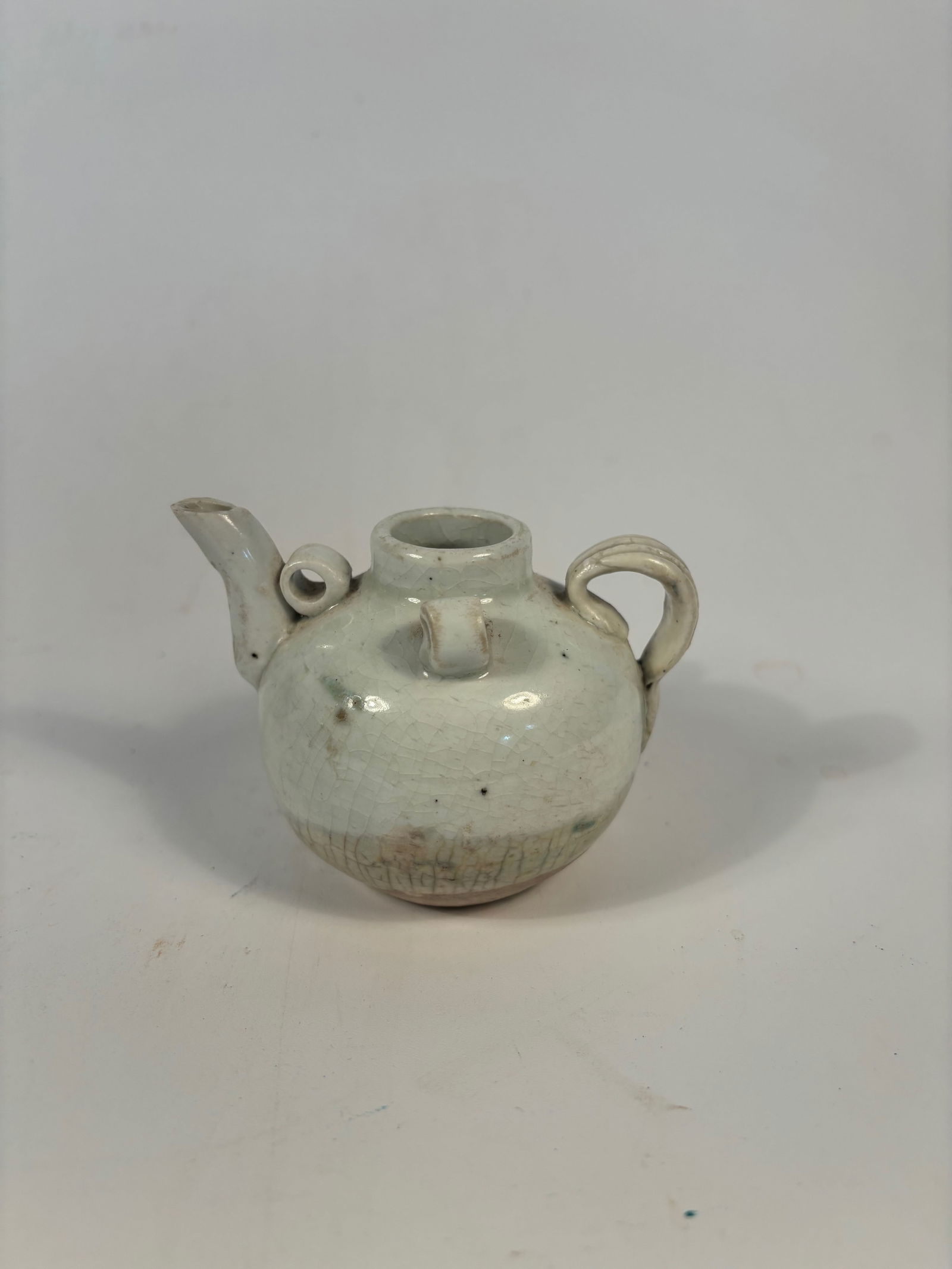 A Chinese Qingbai Ewer: Song to Yuan Dynasty period (circa 12th–14th century). ). It features a rounded body, loop handle, and short spout, with soft celadon glaze typical of early southern Chinese kilns.Dimensions?