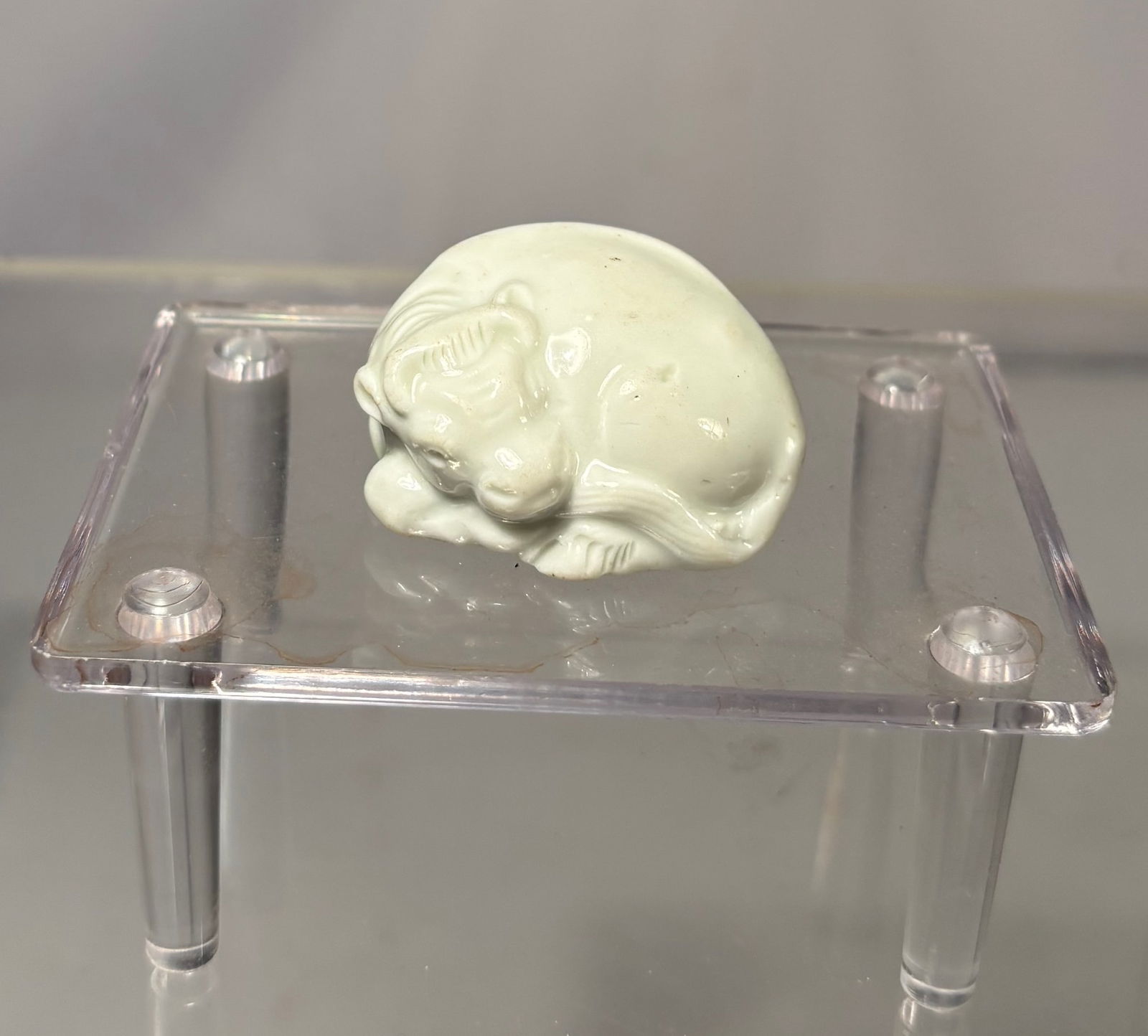 Hirado Porcelain Netsuke of an Ox (Ushi), Japan, Meiji Period: Japanese porcelain netsuke carved in the form of an ox (Ushi), shown in a recumbent pose with a rounded body and calm expression. The figure is finished in a soft white glaze with finely modeled