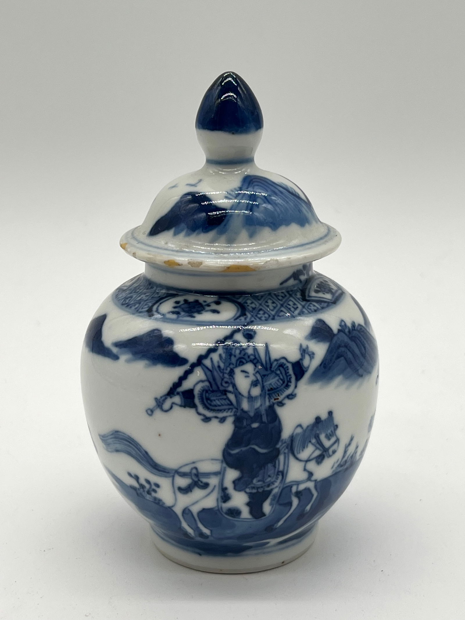A Chinese blue and white mini porcelain jar with KangXi Mark: Qing dynasty (1644-1912); The figure on horseback, wielding a weapon or in a dynamic pose, may represent a historical or legendary hero, a common motif. Dimensions?Height: 5 3/4 inches