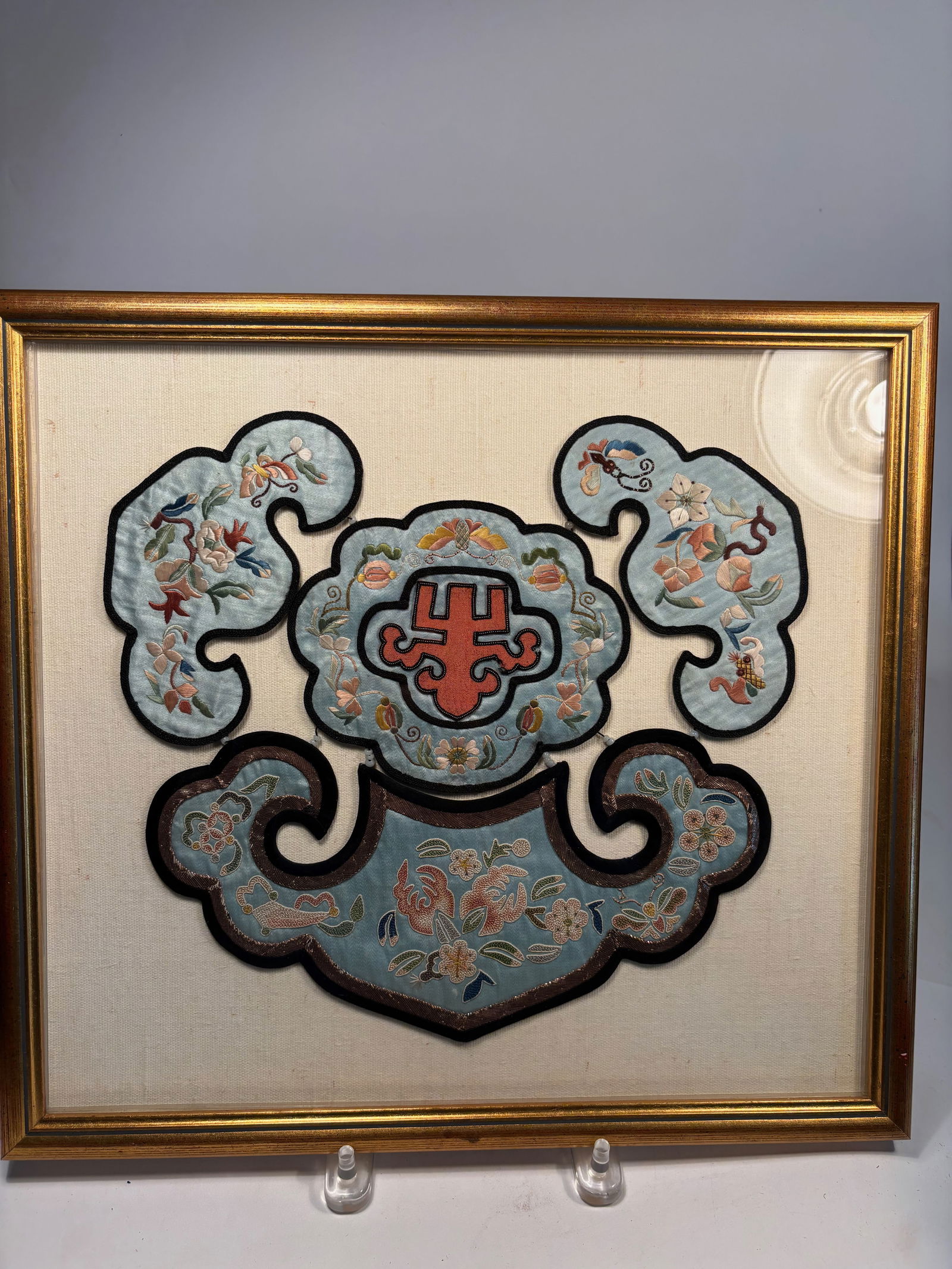 A Framed Chinese Silk Embroidery Panel with Auspicious Motifs: Qing Dynasty (1644-1912); A Chinese silk embroidery panel, likely repurposed from a Qing dynasty rank badge or ceremonial robe ornament. Finely worked in satin stitch and couching on a pale blue silk