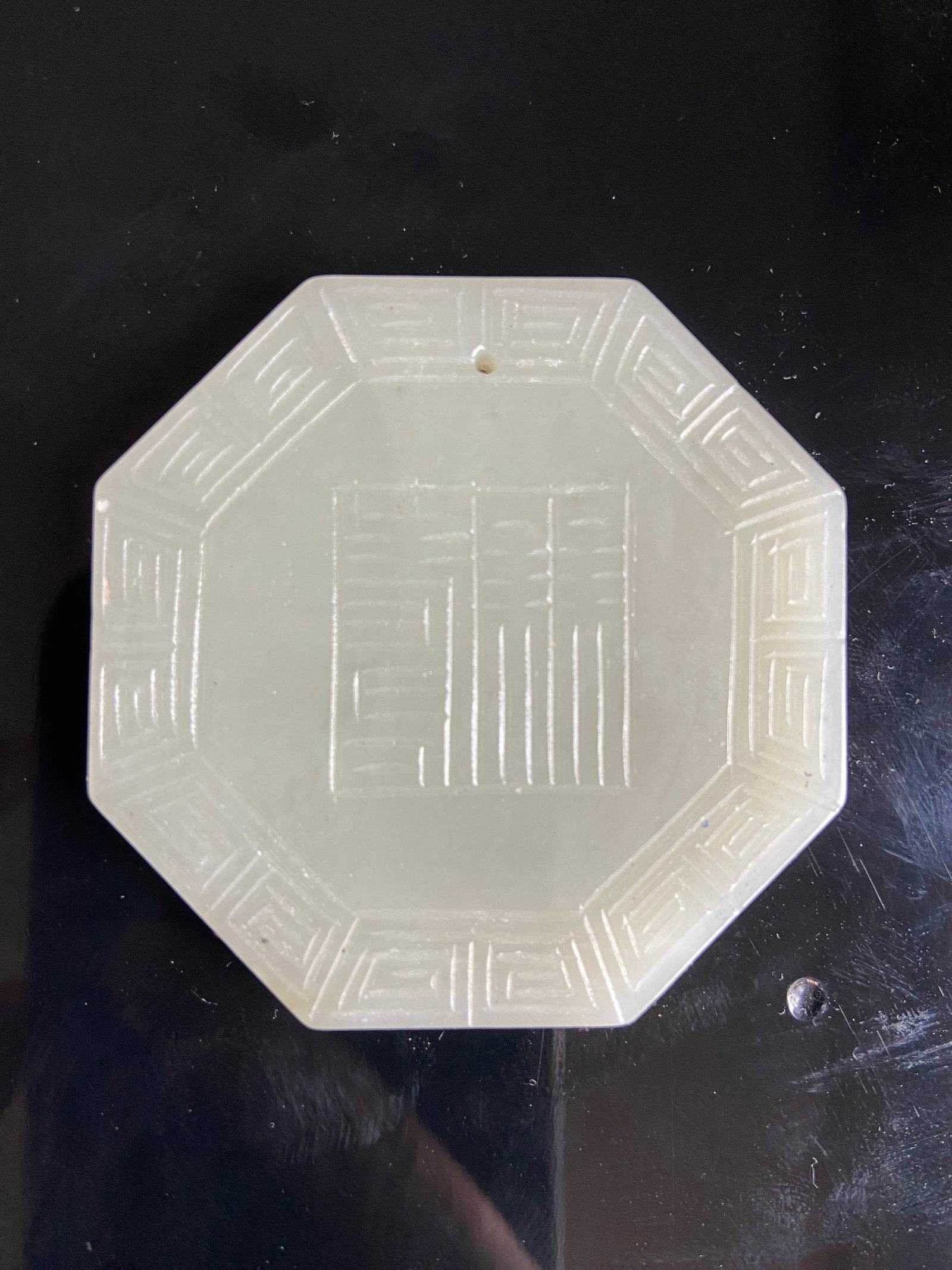 A CHINESE OCTAGONAL SHAPE WHITE NEPHRITE JADE PLAQUE: Qing Dynasty (1644-1912);The OCTAGONAL SHAPE Plaque is finely carved with Chinese characters and flower motifs;The jade is of an even pale tone.Dimensions? Height: 5.5cm ;thickness: 6mm.