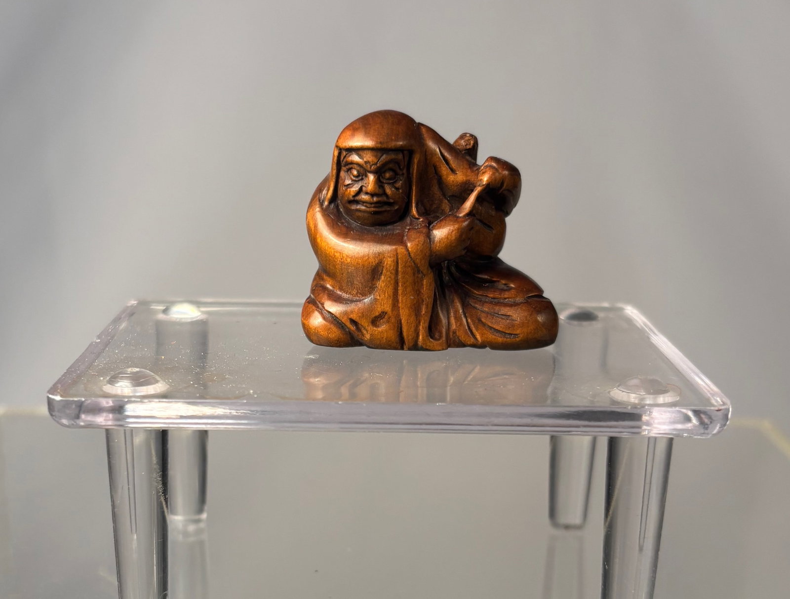 A Japanese Boxwood Netsuke of a Hooded Rakan with Rat at Shoulder, Signed Gyokusan: Meiji period (19th century), Finely carved Japanese netsuke in boxwood depicting a seated hooded rakan (arhat), shown enveloped in flowing robes with knees drawn up and an expressive, contemplative fa
