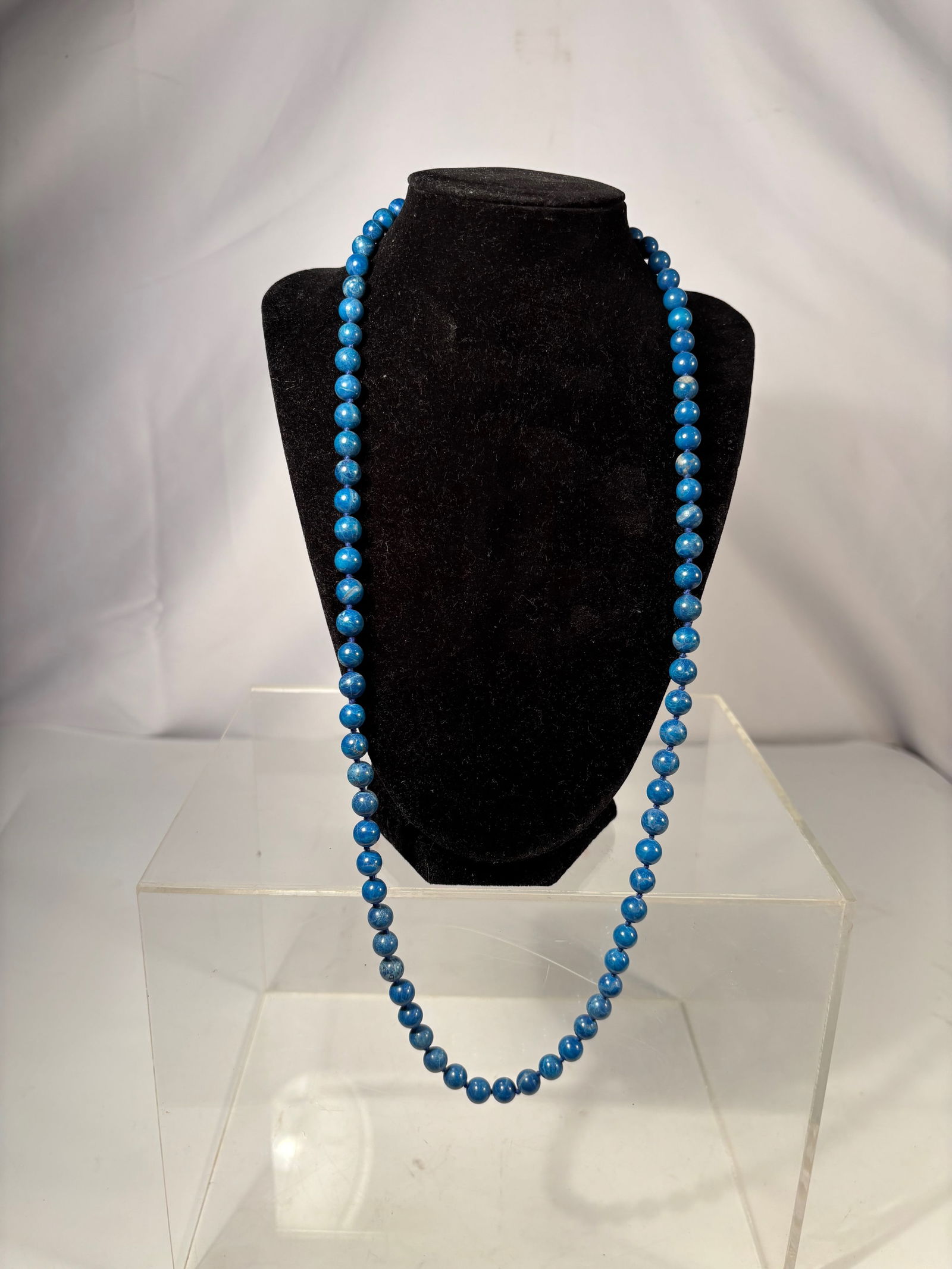 A Lapis Lazuli Bead Necklace: This necklace is composed of natural lapis lazuli round beads, displaying a deep blue color with natural mineral veining and tonal variation characteristic of lapis lazuli. The beads are individually