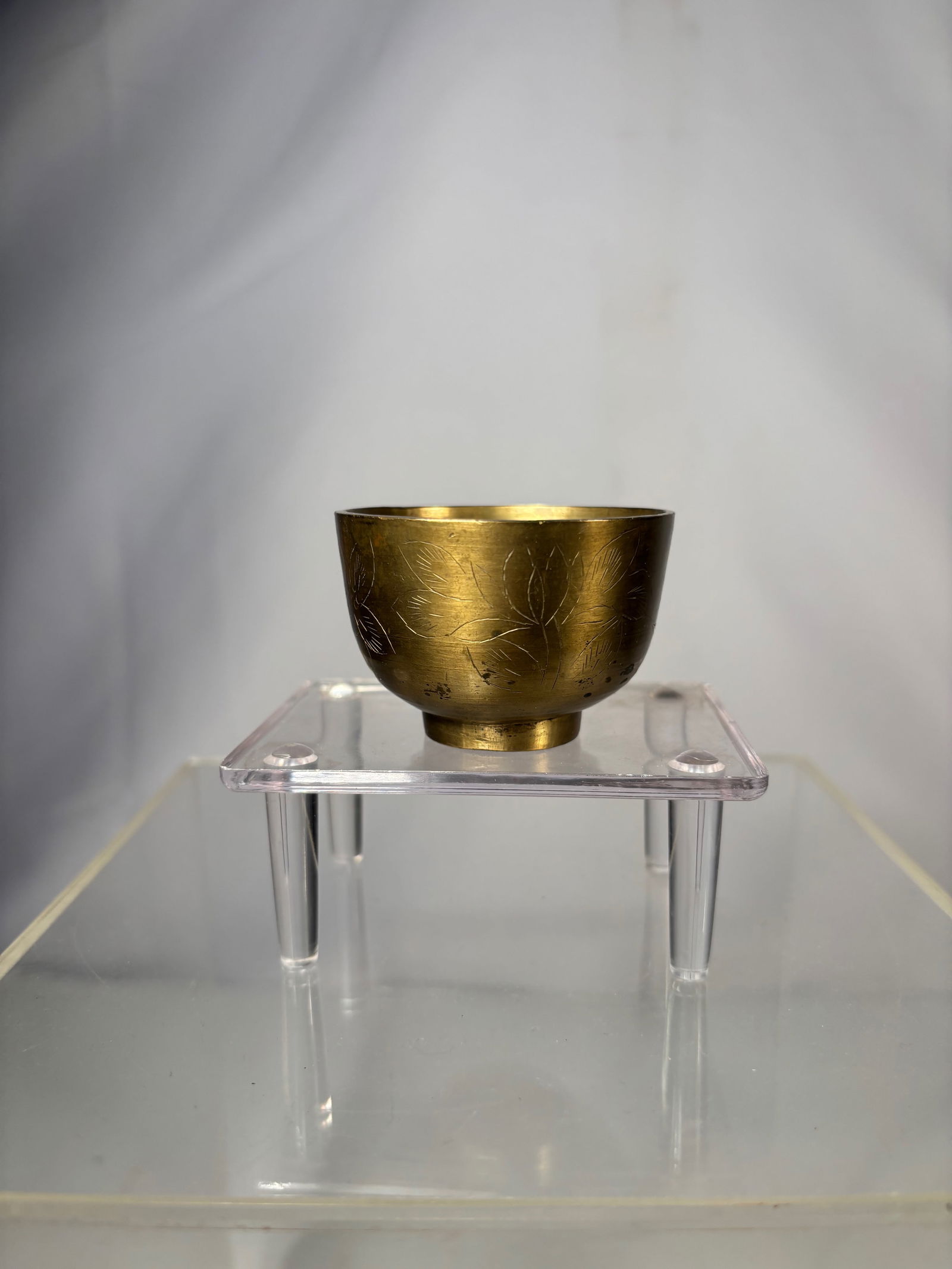A Chinese Carved Brass Wine Cup: Qing Dynasty (1644-1912); A Chinese small brass cup or bowl of simple rounded form, raised on a short circular foot. The interior and exterior display a warm brass surface with natural patina, toning,