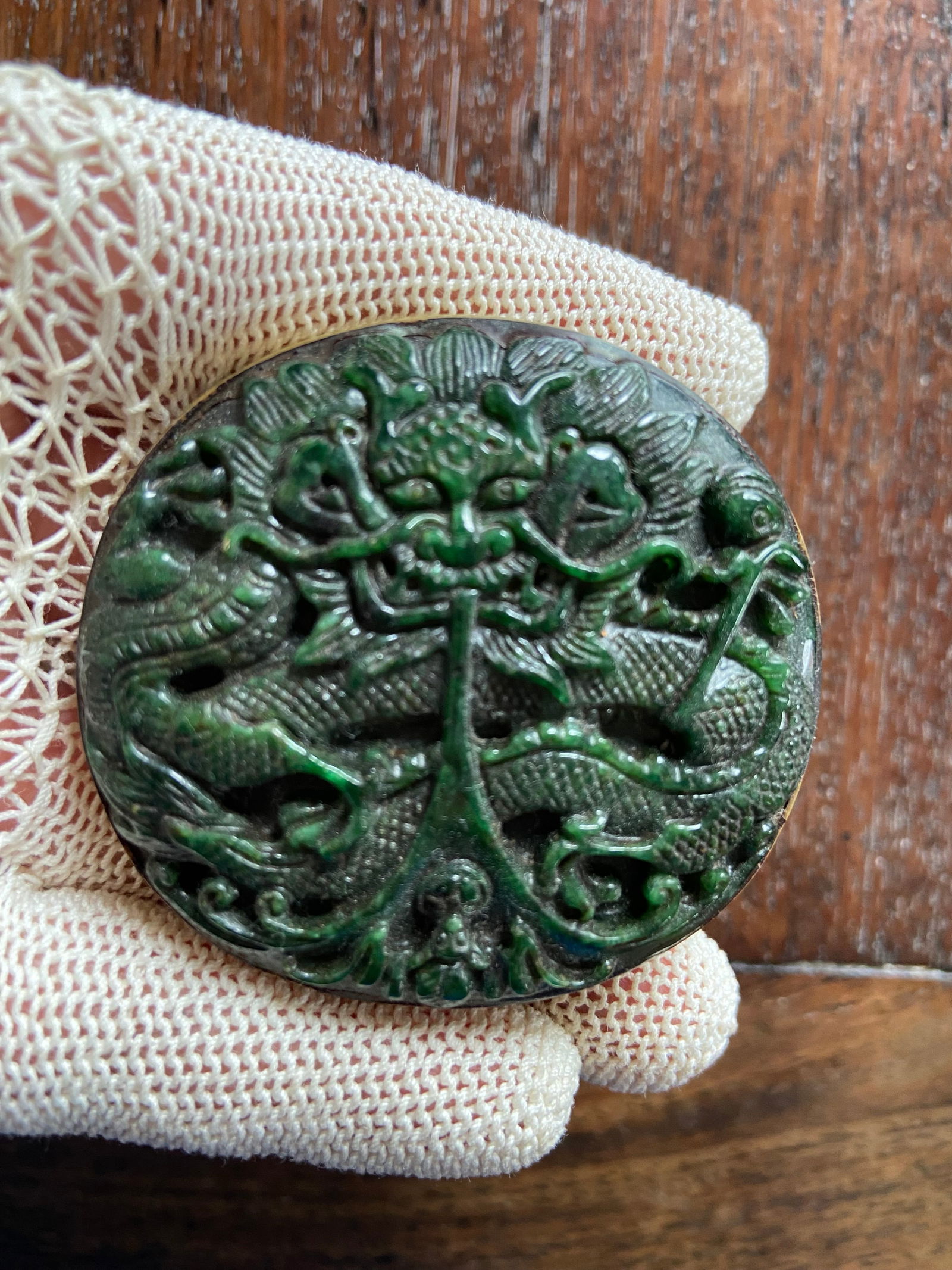 A Chinese hand carved green jade/ Jadeite bronze buckle: Qing Dynasty (1622-1912); the buckle could feature symbolic creatures or natural elements like dragons; cloud and other motif.Dimensions? Diameter: 5.5cm
