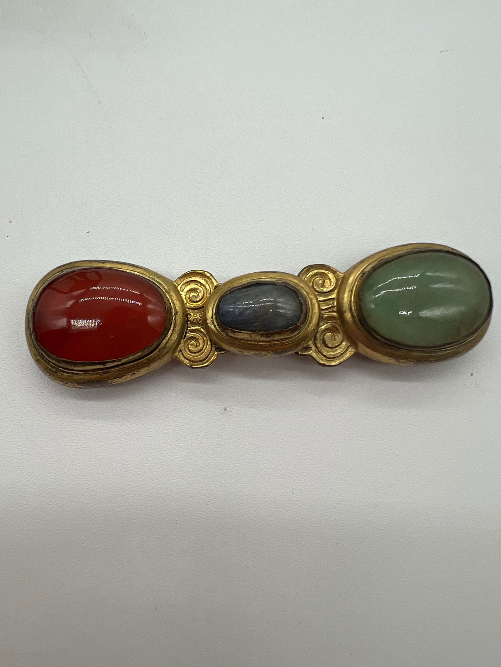 A Chinese Gilt Bronze Jeweled Belt Buckle: Qing Dynasty (1644-1912); The buckle featuring three oval stones set in what appears to be a gilded metal frame. The stones look like they might be semi-precious stone like jade , carnelian and lapis.