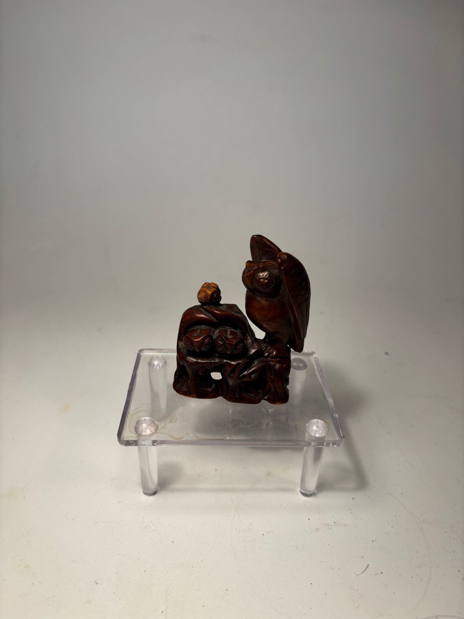 A Japanese Boxwood Netsuke of an Owl and Owlets: Meiji Period or later (late 19th–early 20th century); Finely carved in the round, the netsuke depicts a standing owl perched atop a gnarled tree trunk, beneath which several owlets peer out from the