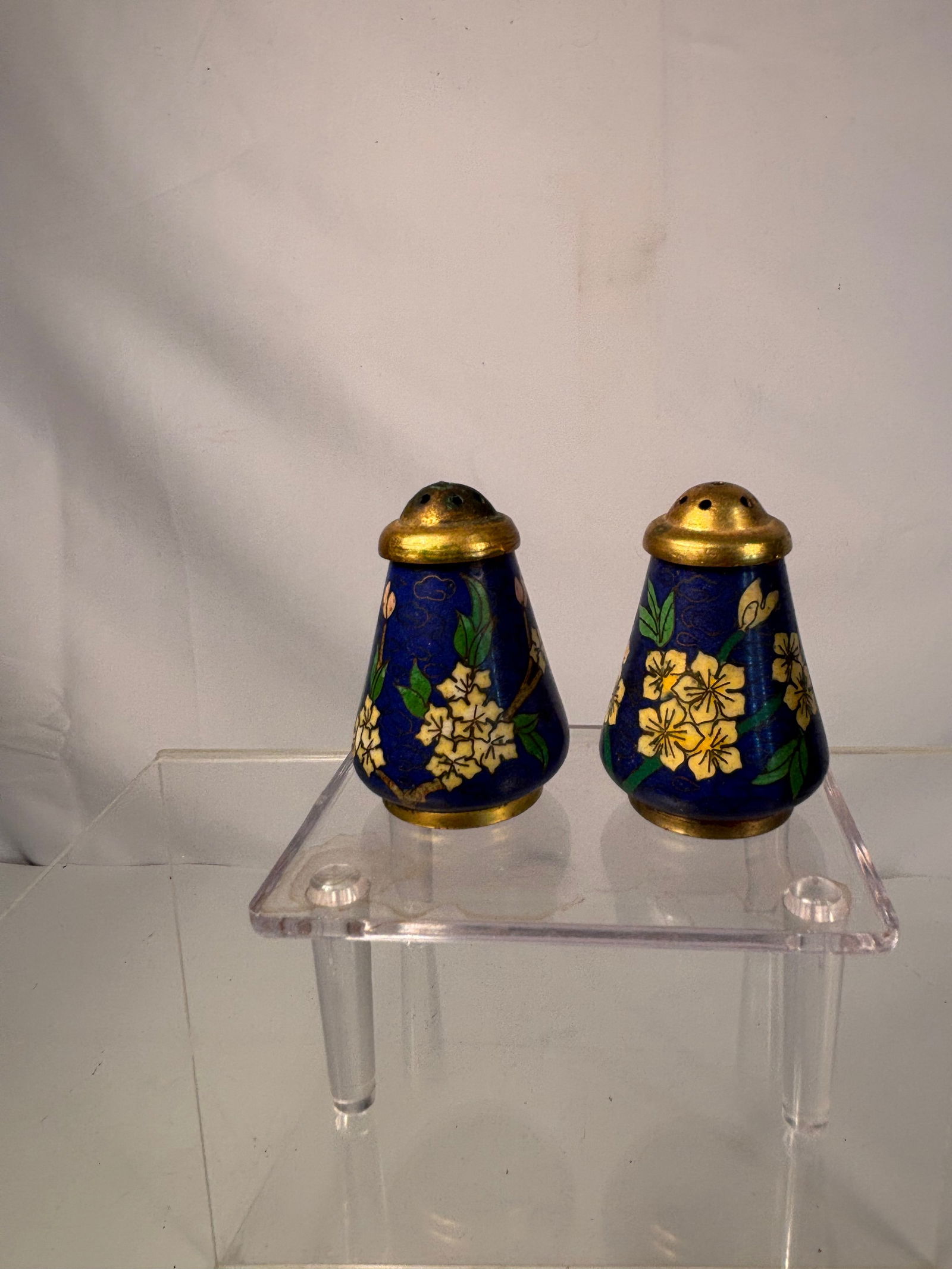 Pair of heavy Chinese Cloisonné Enamel Salt and Pepper Shakers, 19th Century: A charming pair of miniature Chinese cloisonné enamel shakers, each decorated with vivid yellow floral motifs and green leaves on a rich cobalt blue ground. Fitted with pierced gilt-brass tops and tu