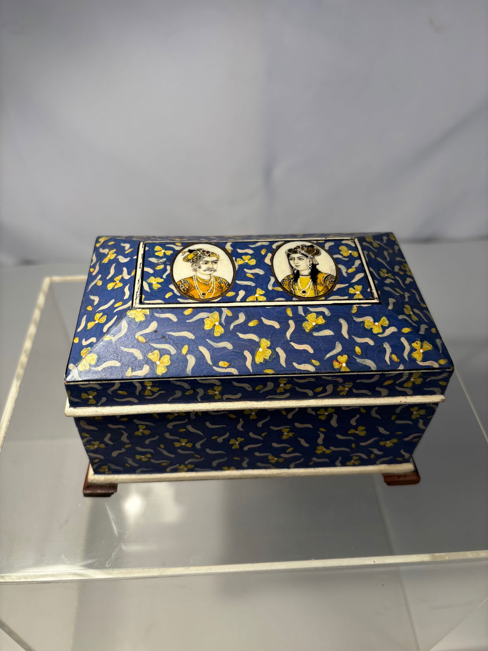 An indian hand painted blue enamel wood box: Early 20th century,An Indian hand-painted blue enamel wood box, mid-20th century. The rectangular box with hinged lid decorated in blue enamel with floral scrolls, the top centered by circular portrai