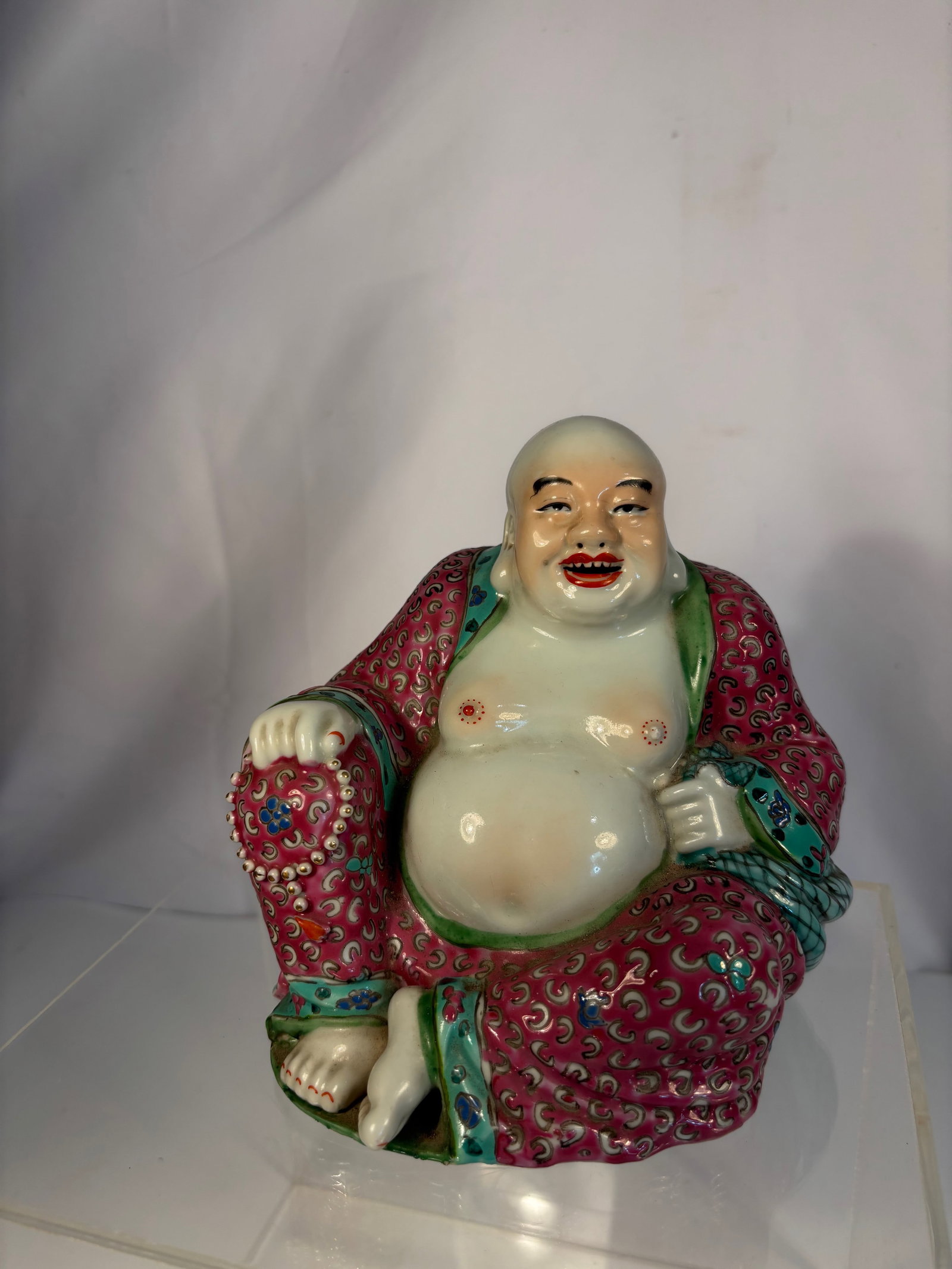 A Famille Rose Porcelain Figure of Budai, Incised “Zhu Chunfa Zao?? Mark: Early 20th Century; Finely modeled and enameled porcelain figure of Budai, depicted seated with one leg raised and his robe loosely draped, exposing his ample belly and joyful expression. The figure i