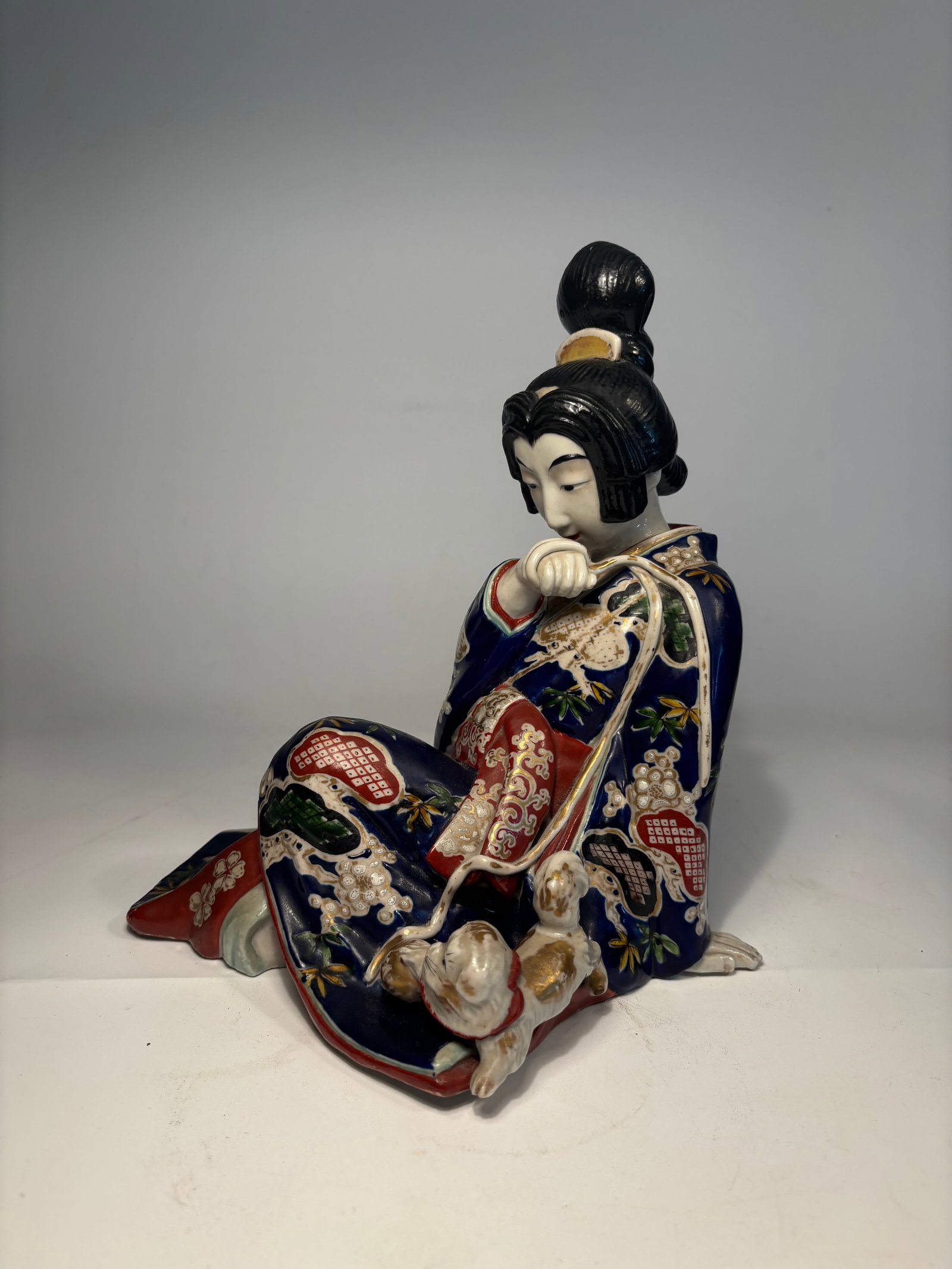 A Seated Geisha with Pekingese, Satsuma, Japan: Meiji period (1868-1912). Dimensions?Height: 10 inches; Width: 8.5 inches.