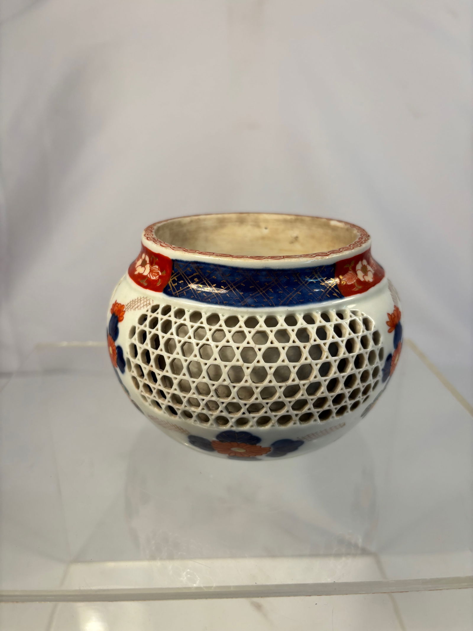 A Japanese Reticulated Porcelain Incense Burner (K?ro), Meiji Period (1868–1912): Of compressed globular form with a short waisted neck and flat rim, the body delicately pierced with a lattice (reticulated) honeycomb design, overglazed with iron-red, cobalt blue, and gilt floral mo