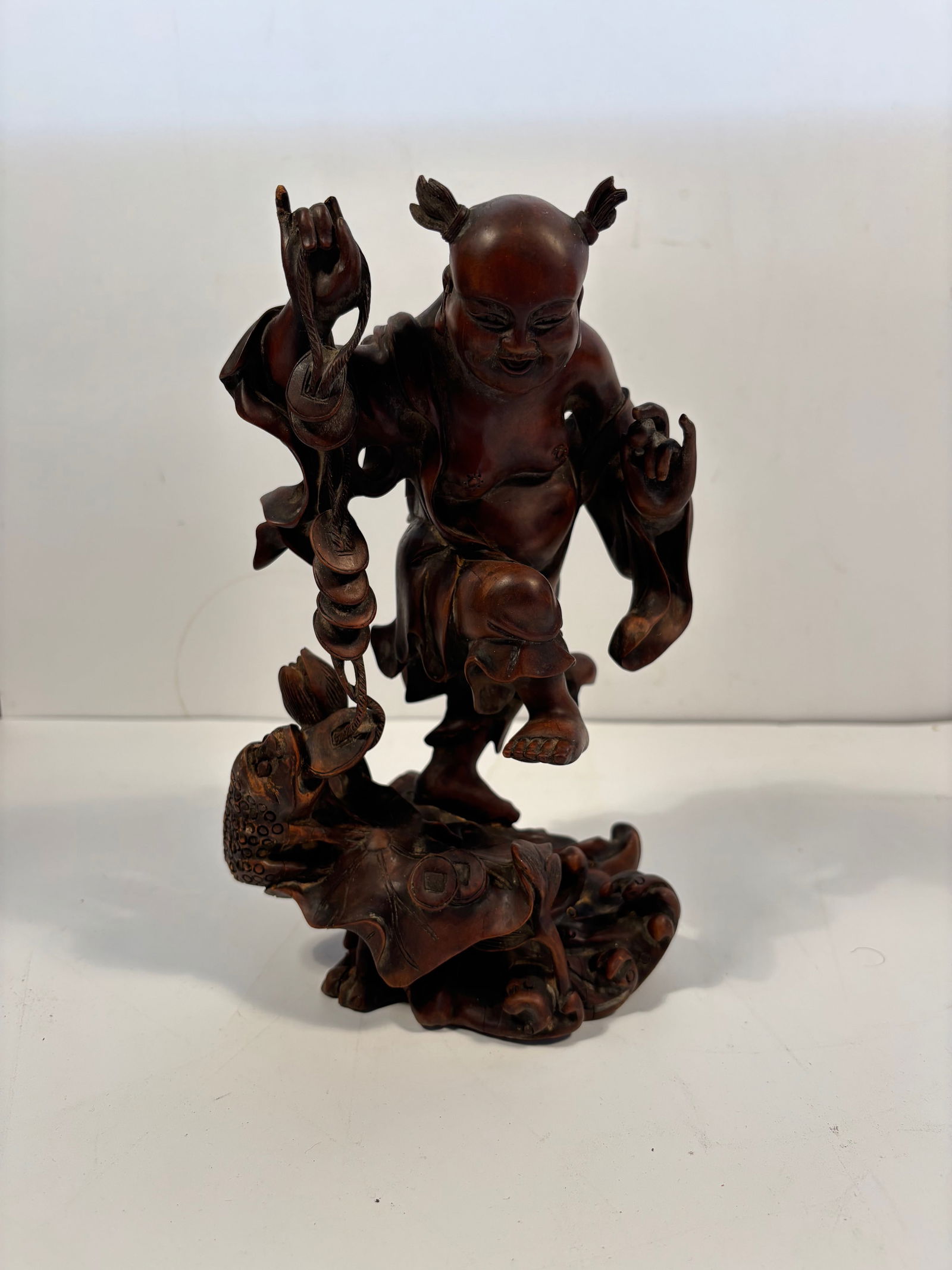 A Chinese hand carvd Child with a Three leg toad boxwood statue: Qing Dynasty (1644-1912), The joyful expression and hairstyle suggest the figure is a child deity or immortal.Dimensions? Height: 9.5 inches.
